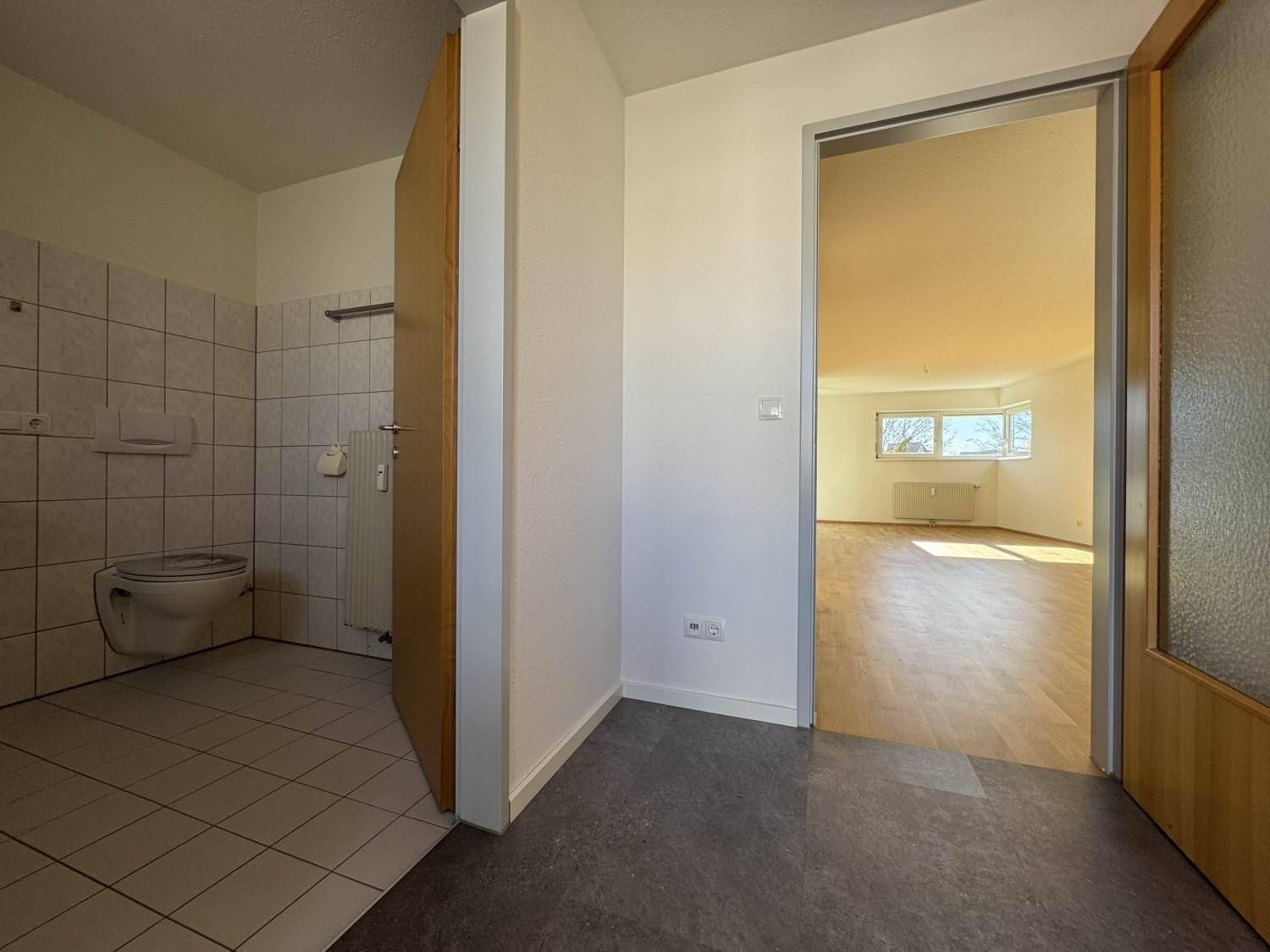 Heller Eingangsbereich mit Fliesenboden und Zugang zu einem WC sowie einem weiteren Zimmer.