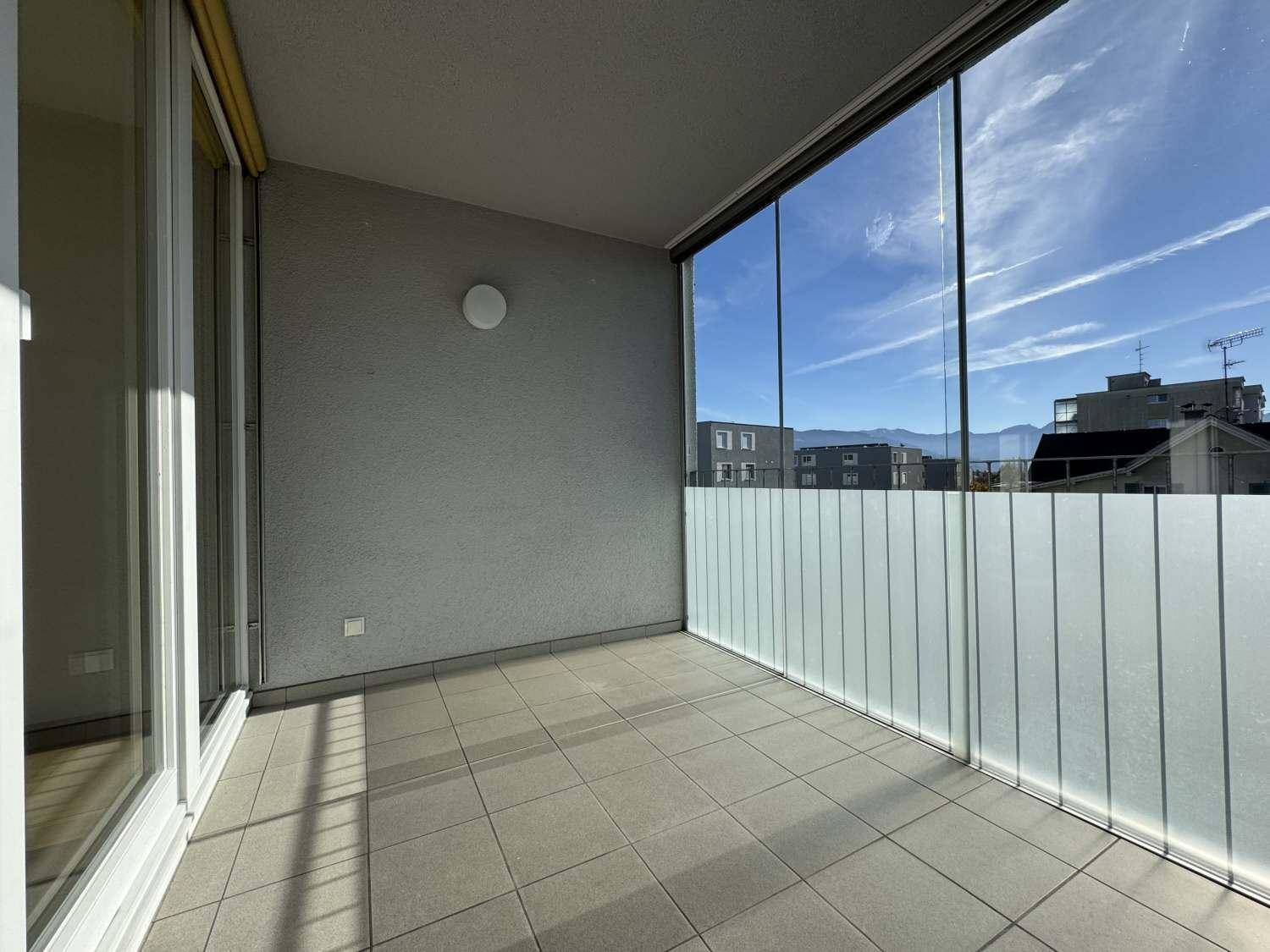 Geräumiger Balkon mit Fliesenboden und Glasbrüstung, bietet einen weiten Blick.