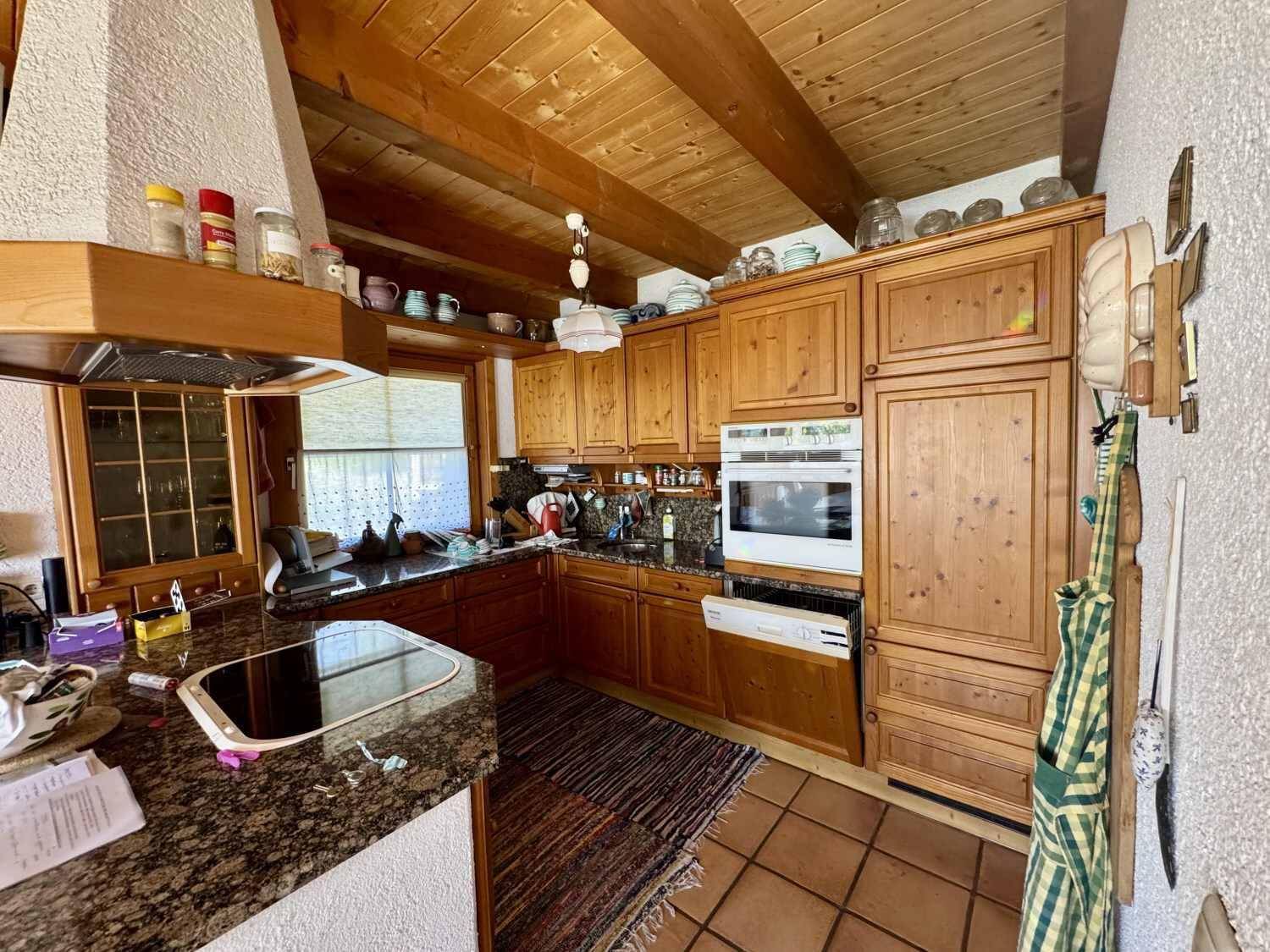 Traditionelle Holzküche mit Granitarbeitsplatten, Einbaugeräten und Terrakottafliesen.