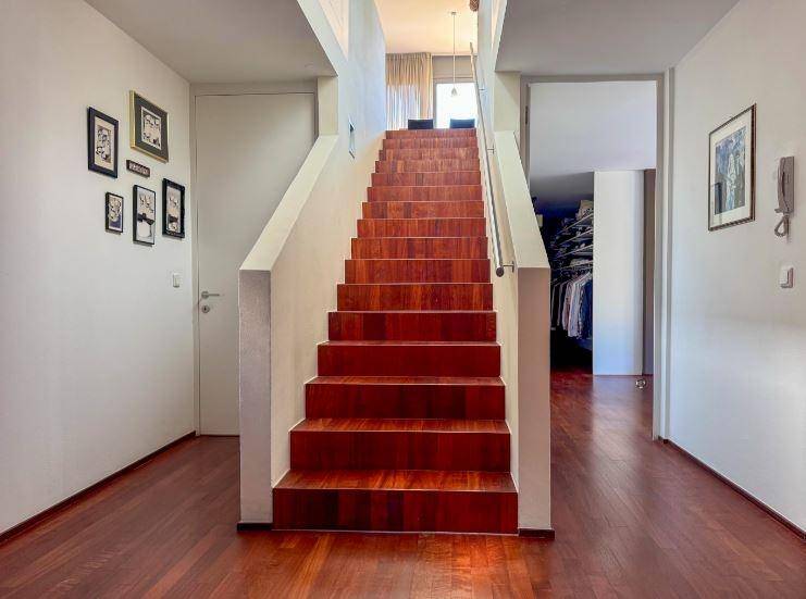 Geräumiger Flur mit Holztreppe, Holzboden und Zugang zu weiteren Räumen.