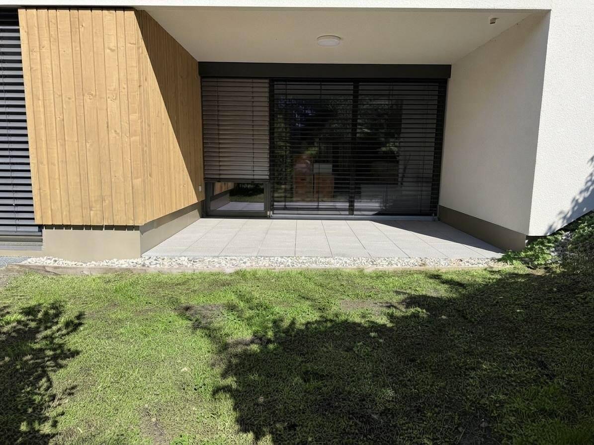 Sonniger Terrassenbereich mit Pflastersteinen und Zugang zu den Innenräumen.