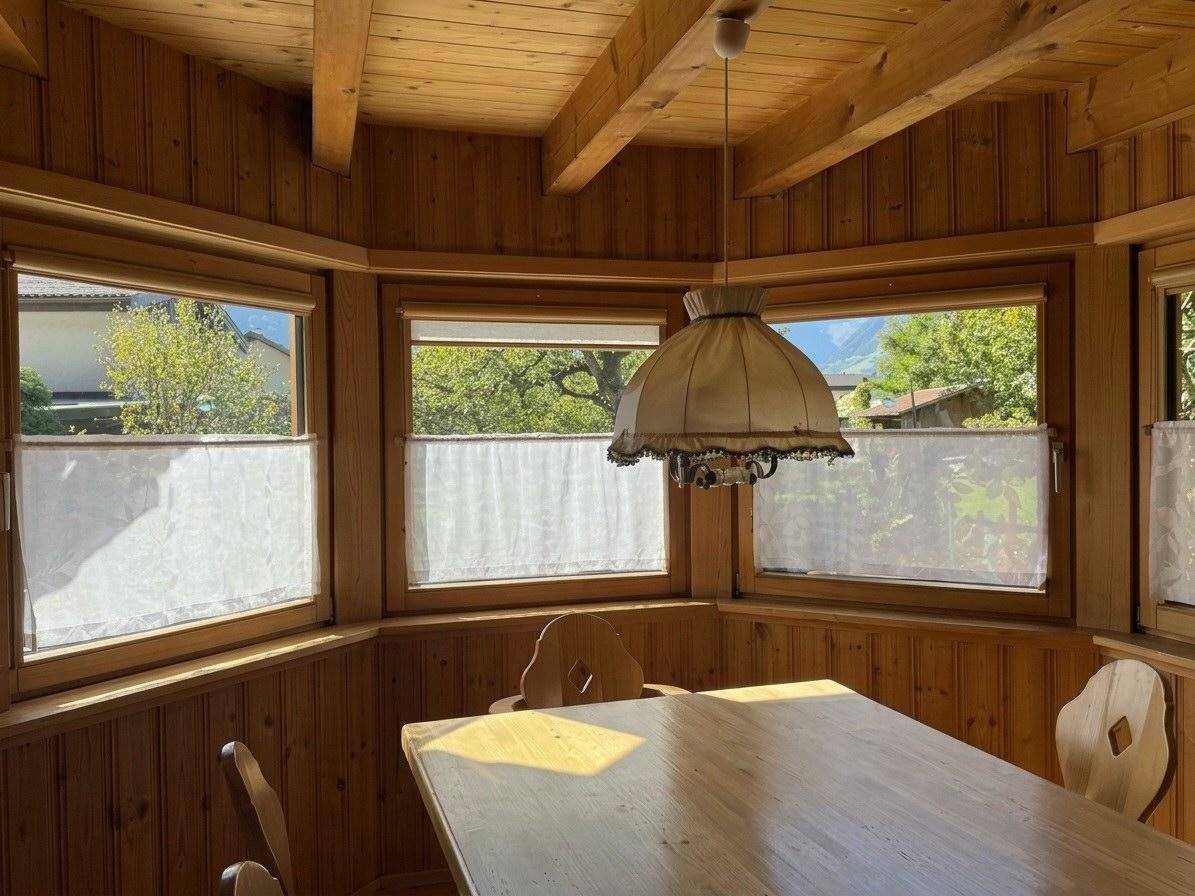 Detailansicht des Essbereichs mit Holzvertäfelung, Fenstern und traditioneller Deckenleuchte.