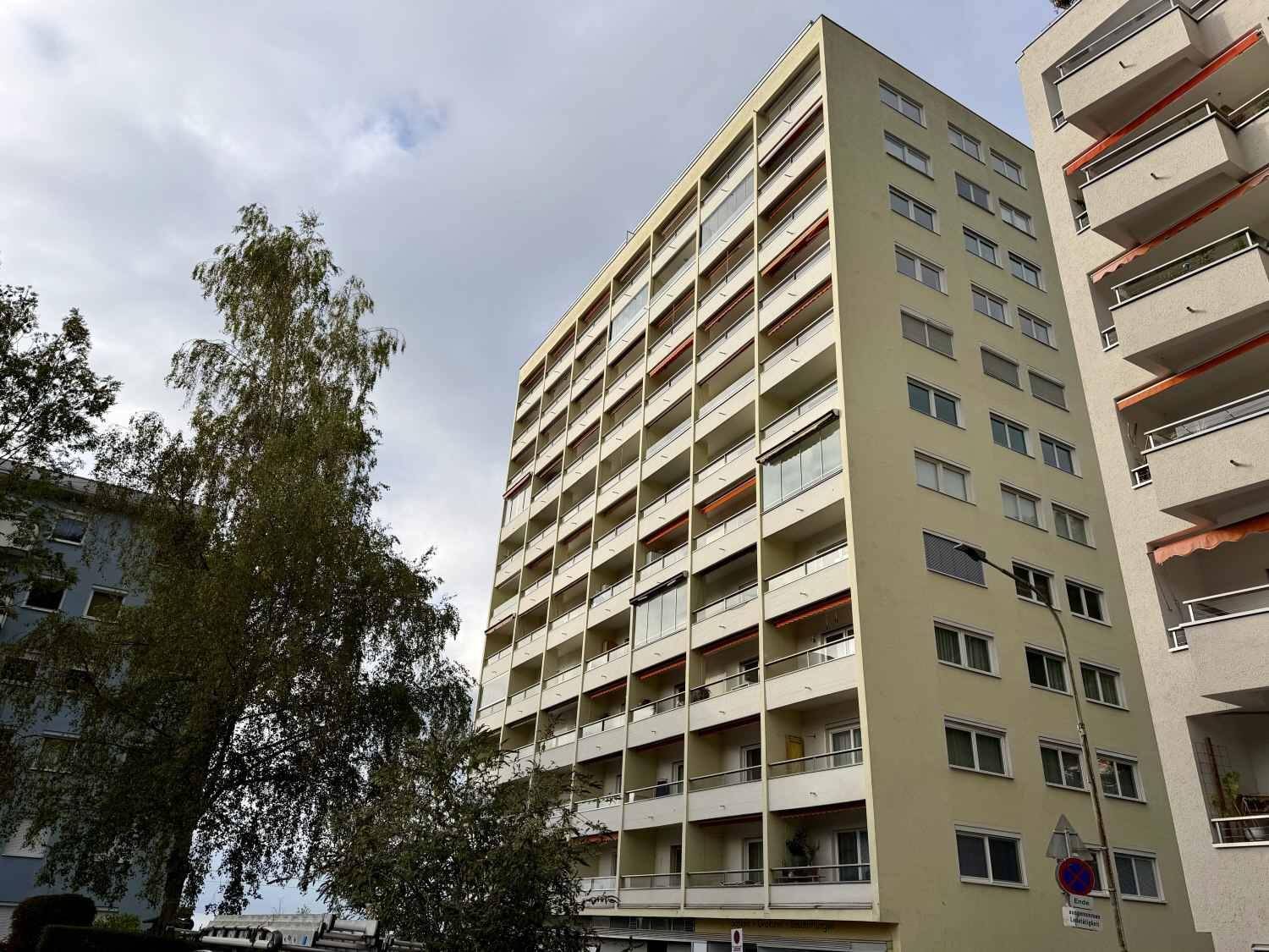 Hohes Wohngebäude mit zahlreichen Balkonen und einer hellen Fassade.