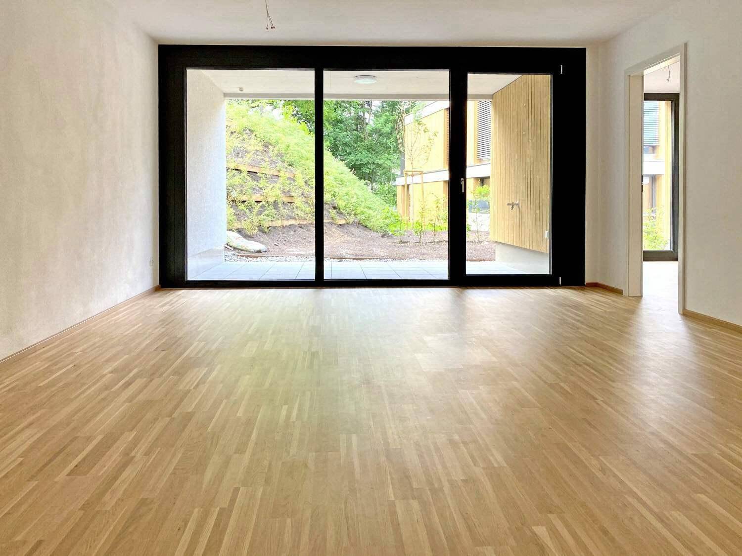 Heller Wohnraum mit Parkettboden und großen Schiebetüren zum Außenbereich.