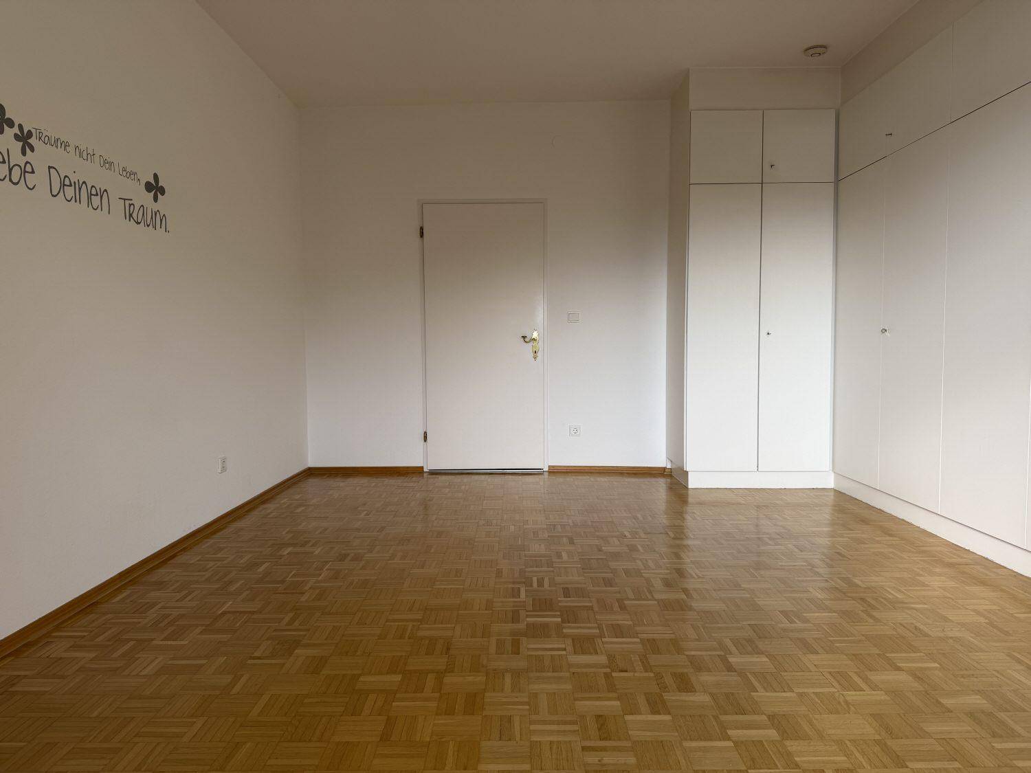 Geräumiges Schlafzimmer mit Parkettboden und praktischen, raumhohen Einbauschränken.