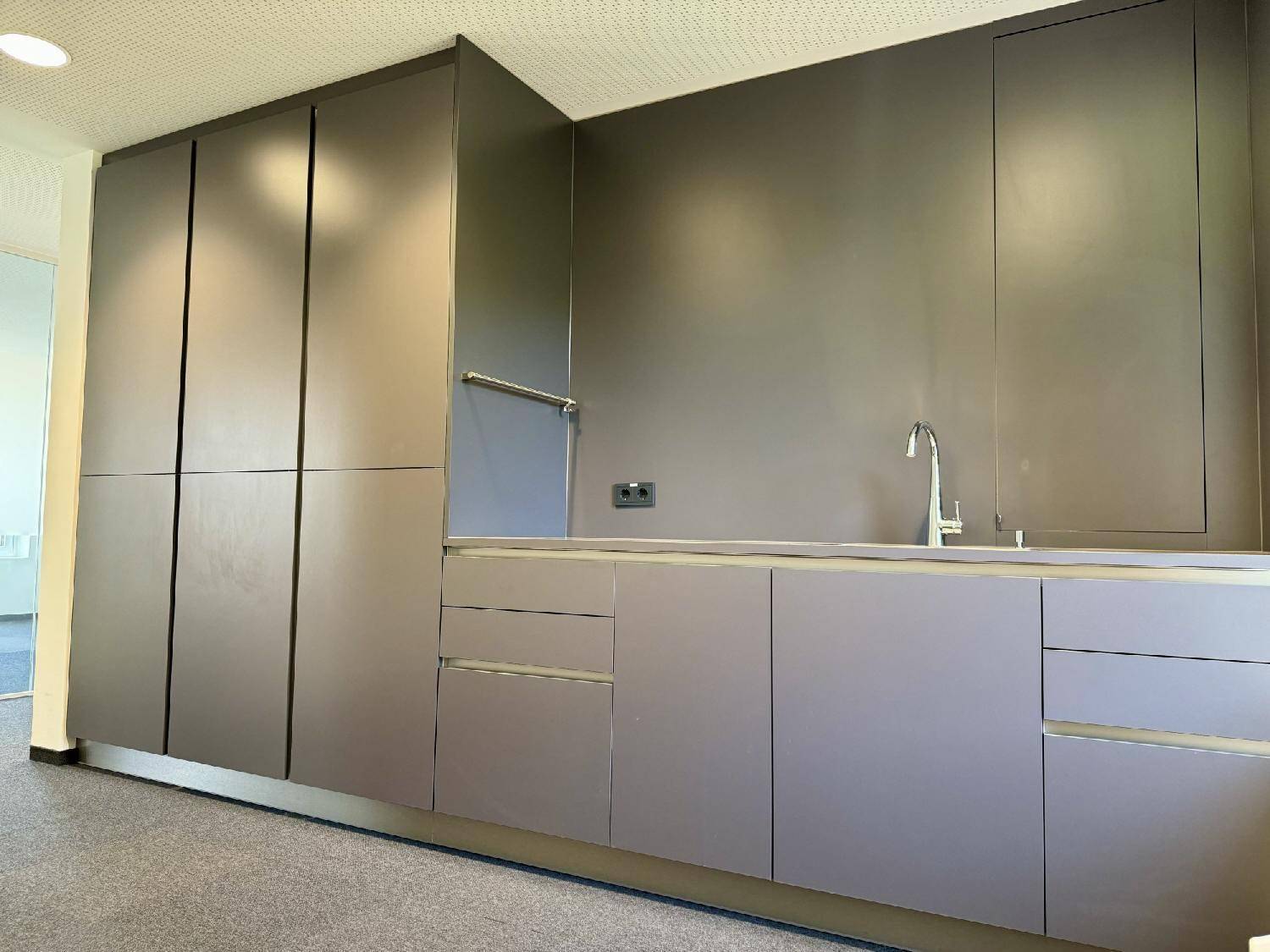 Moderne Küchenzeile mit dunklen Schränken, Spüle und integrierten Staufächern.