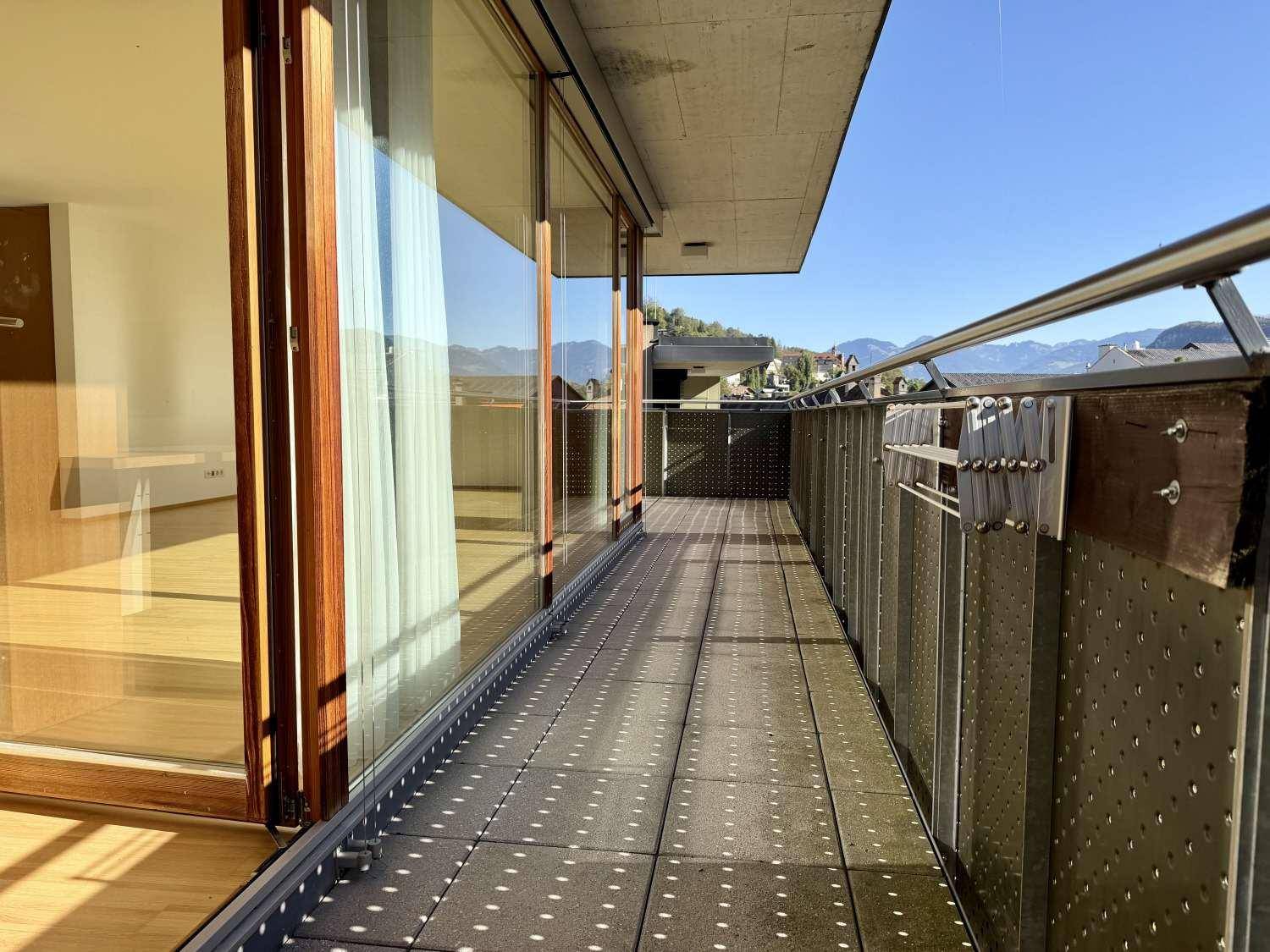 Langer Balkon mit Fliesenboden und Metallgeländer, bietet einen weiten Blick auf die Umgebung.