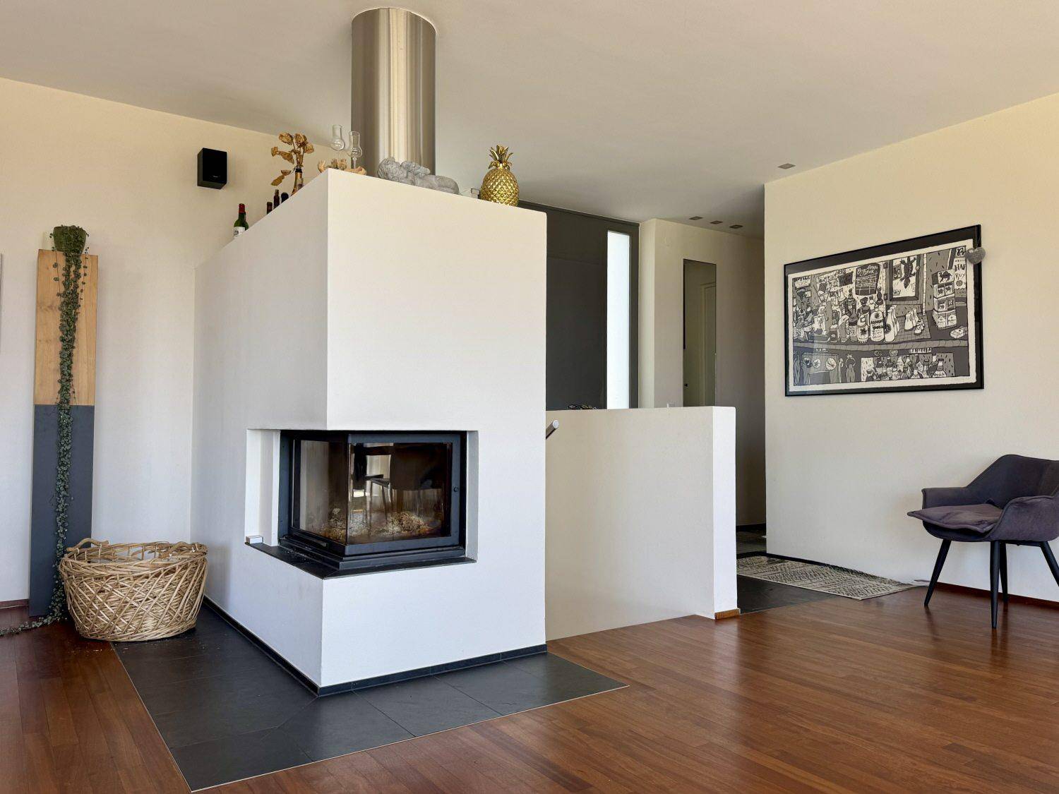 Moderner Kamin als Raumteiler im Wohnbereich mit Holzboden und stilvoller Einrichtung.