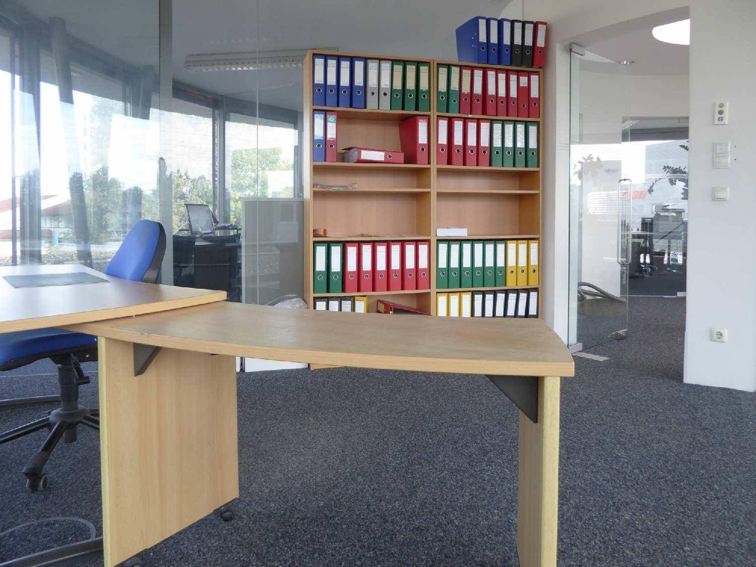 Bürointerieur mit Holzschreibtisch, Bürostuhl und Regalen voller Aktenordner, gut beleuchtet.