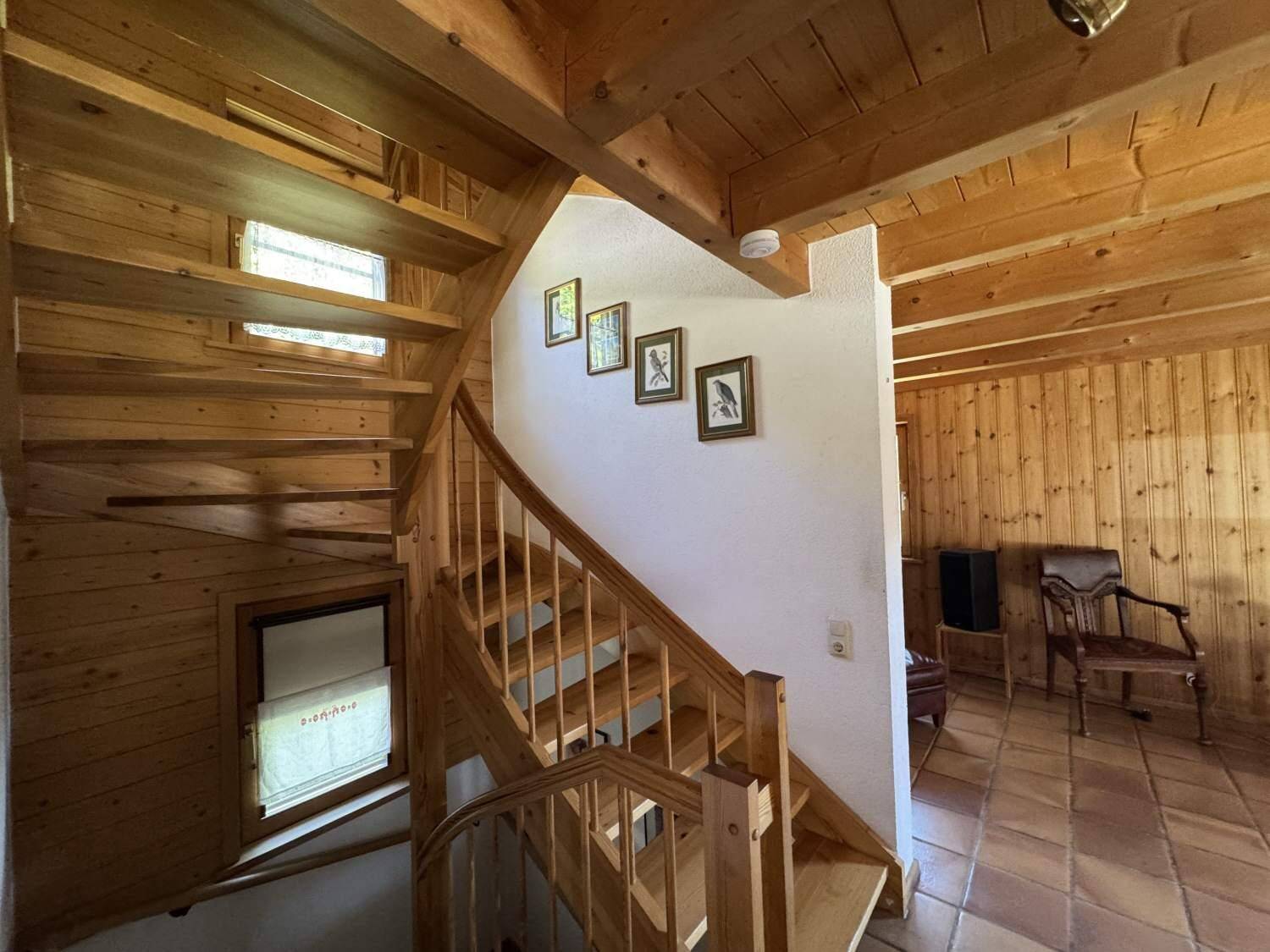 Holztreppe im Landhausstil mit Geländer und Holzbalkendecke.