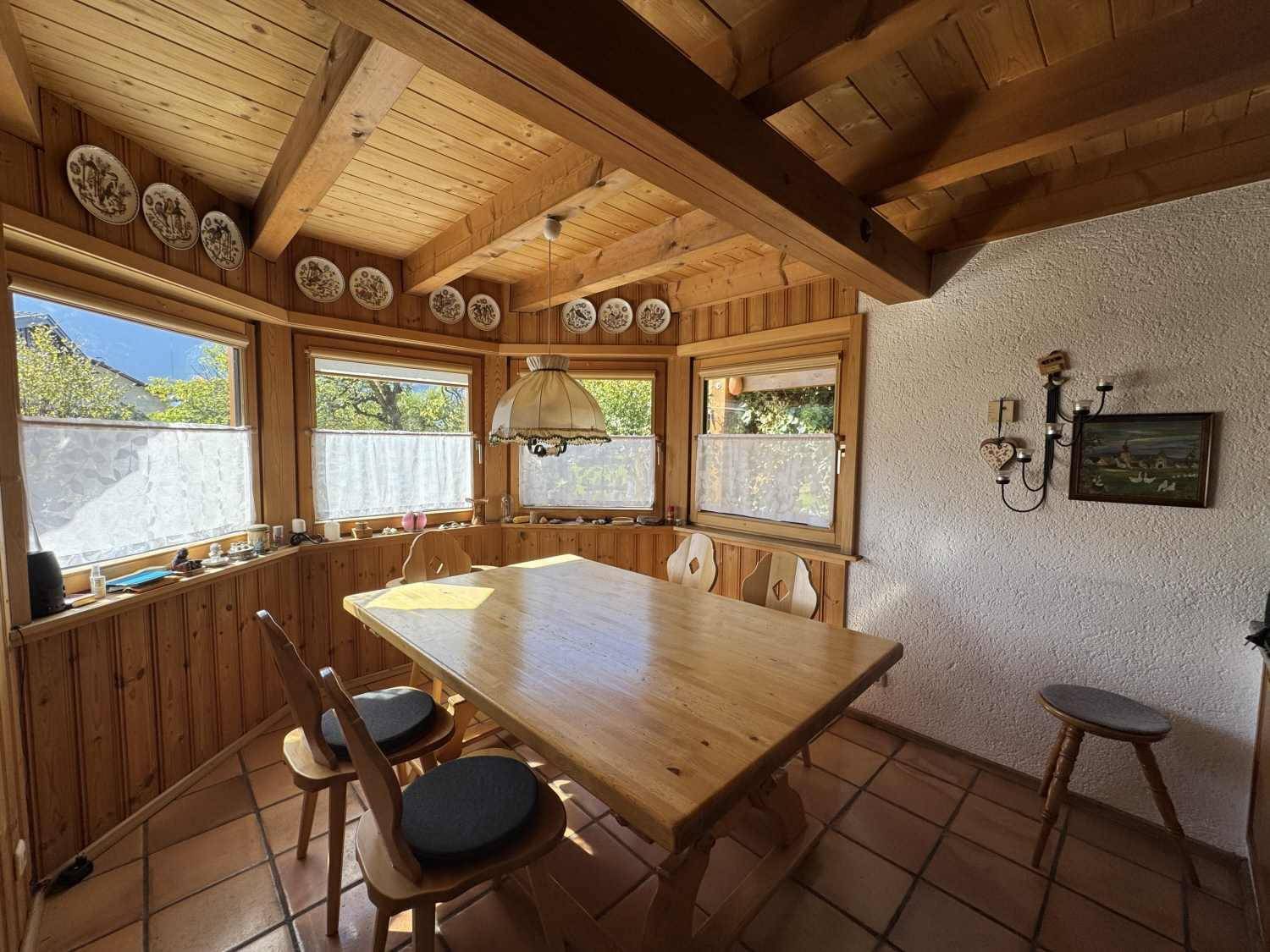 Gemütlicher Essbereich im Landhausstil mit Holztisch, Holzvertäfelung und Terrakottafliesen.