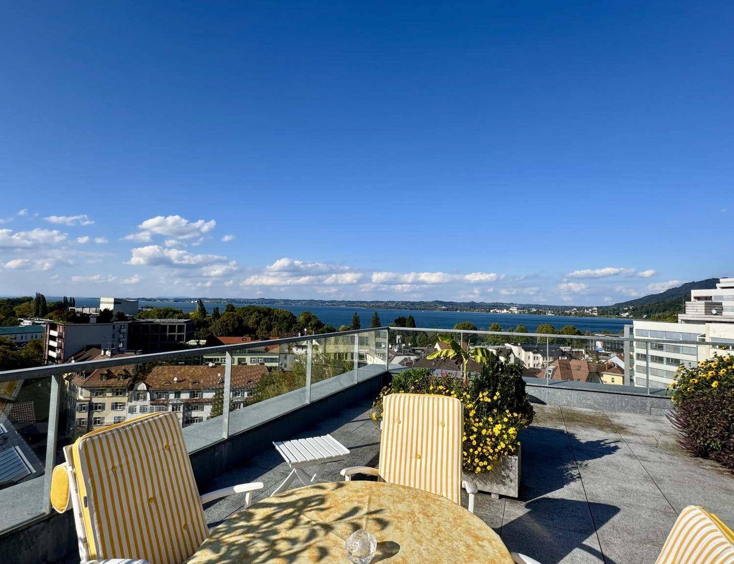 Möblierte Dachterrasse mit bequemen Stühlen und einem atemberaubenden Blick auf den See und die Stadt.
