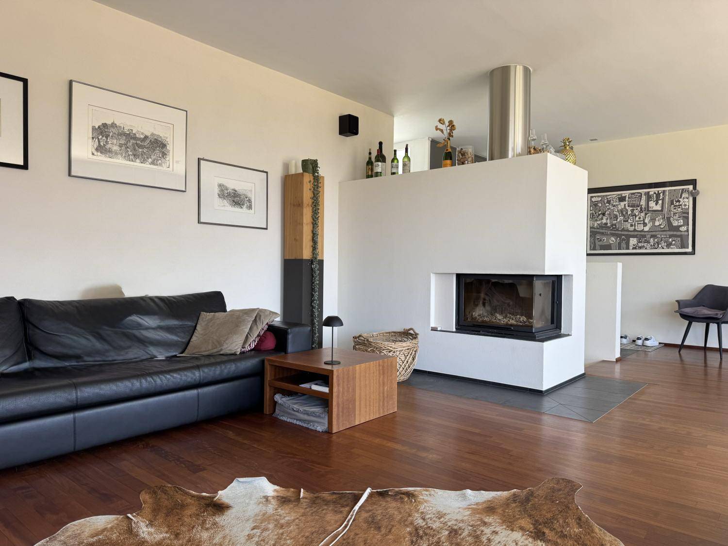 Gemütliches Wohnzimmer mit Holzboden, modernem Kamin und bequemer Ledercouch.