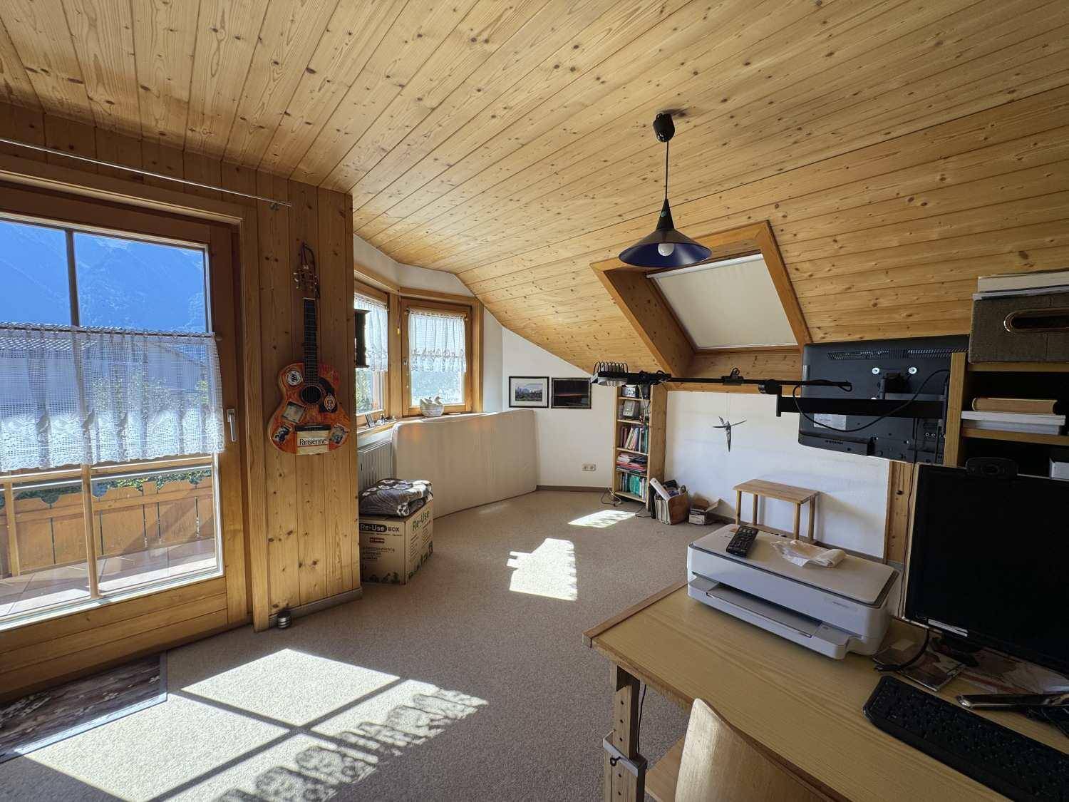 Helles Schlafzimmer im Dachgeschoss mit Teppichboden, Holzdachschrägen und Balkonzugang.