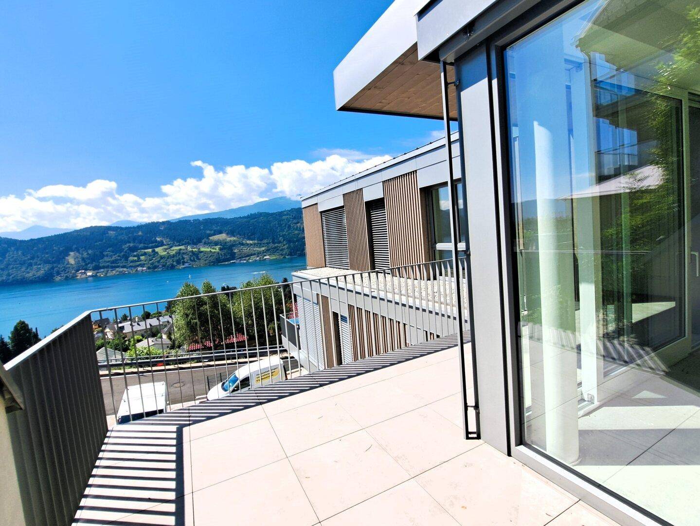 Geräumige Terrasse mit modernem Geländer und weitem Blick über den See und die umliegende Landschaft.