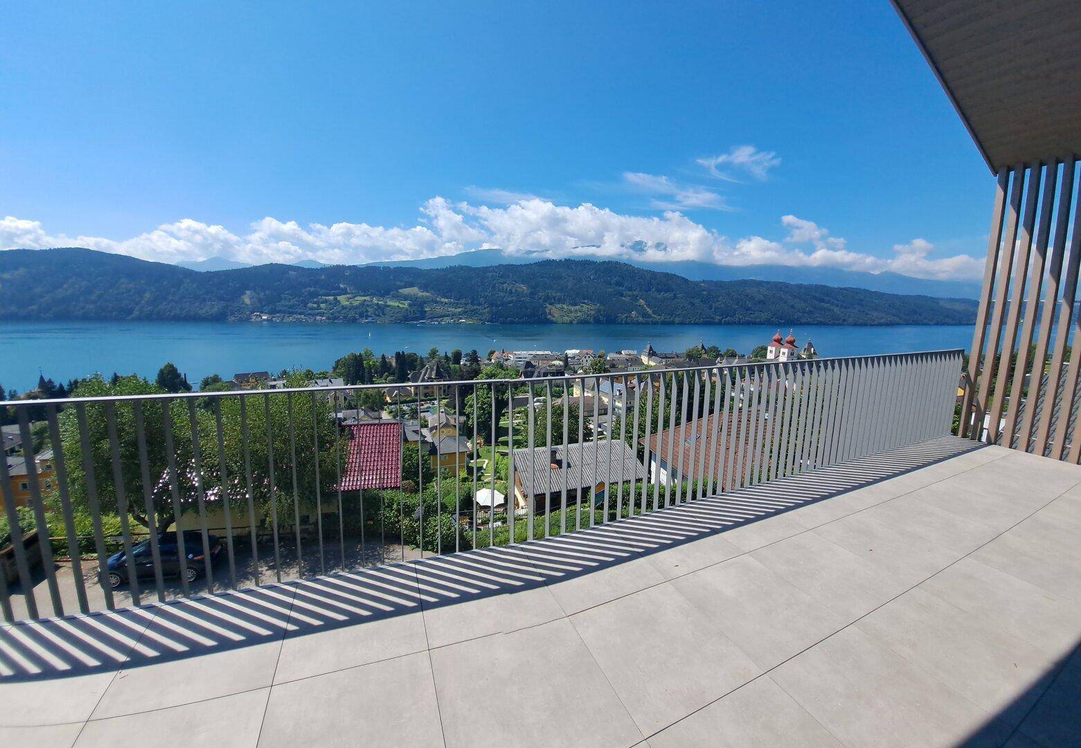 Geräumige Terrasse mit Fliesenboden und atemberaubendem Blick auf den See und die umliegenden Berge.