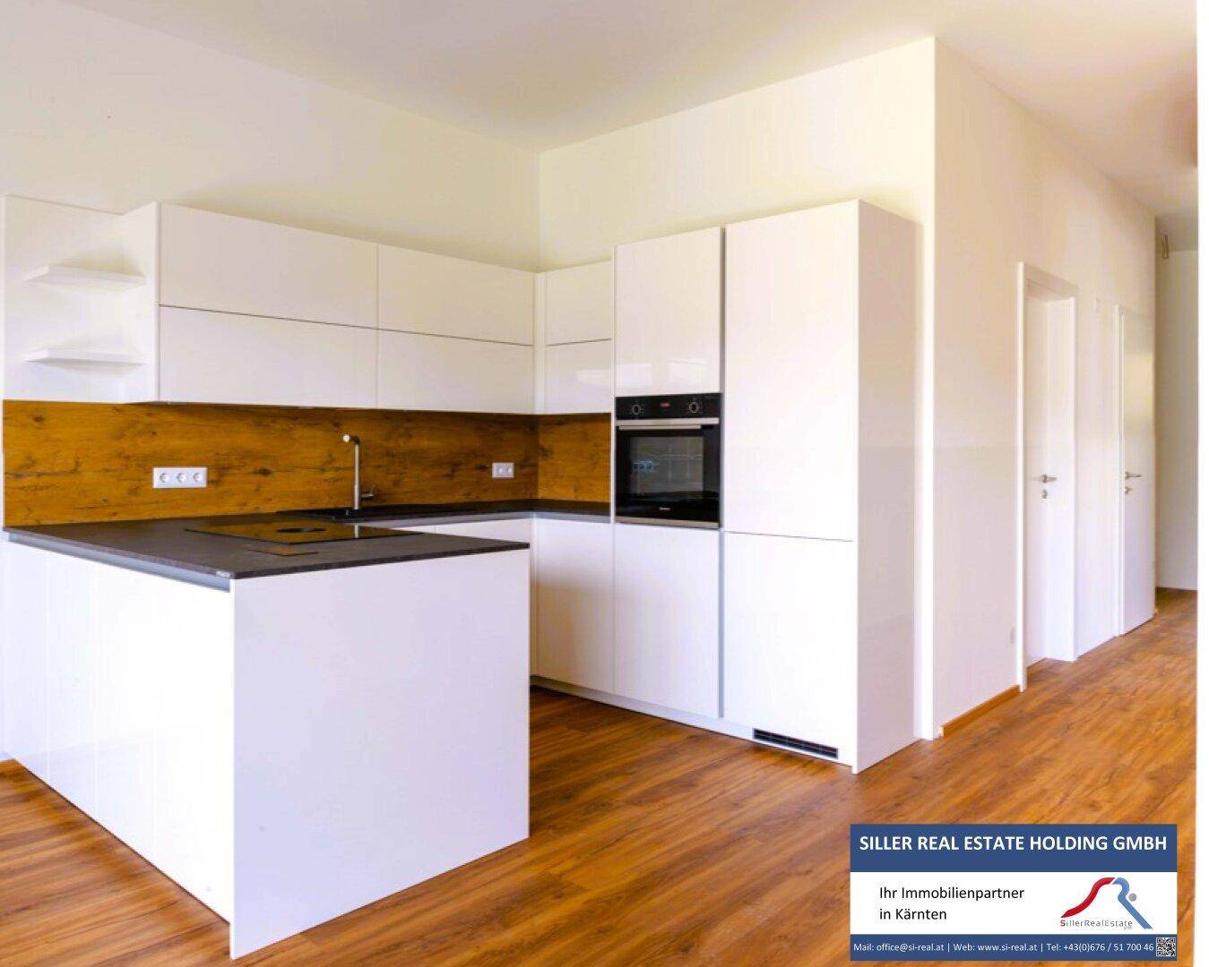 Moderne, helle Küche mit weißen Hochglanzfronten, Holzakzenten und integrierten Geräten.