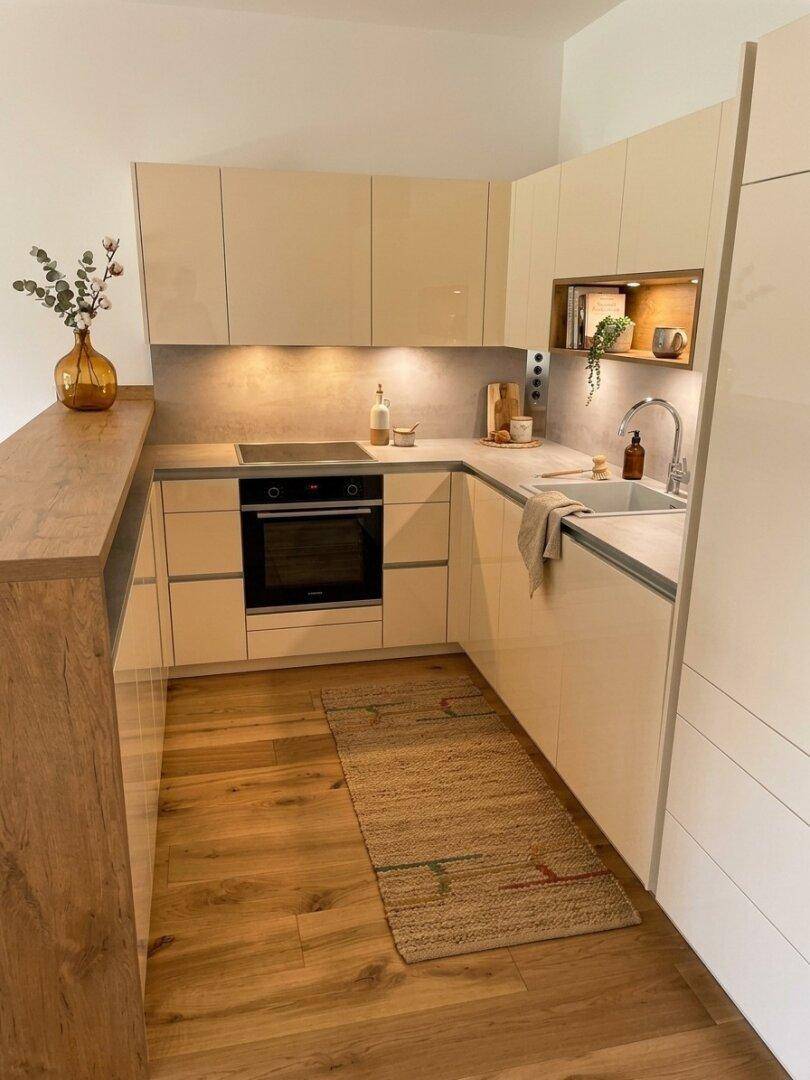 Moderne Einbauküche mit hellen Schränken, Induktionskochfeld und Holzarbeitsplatte.