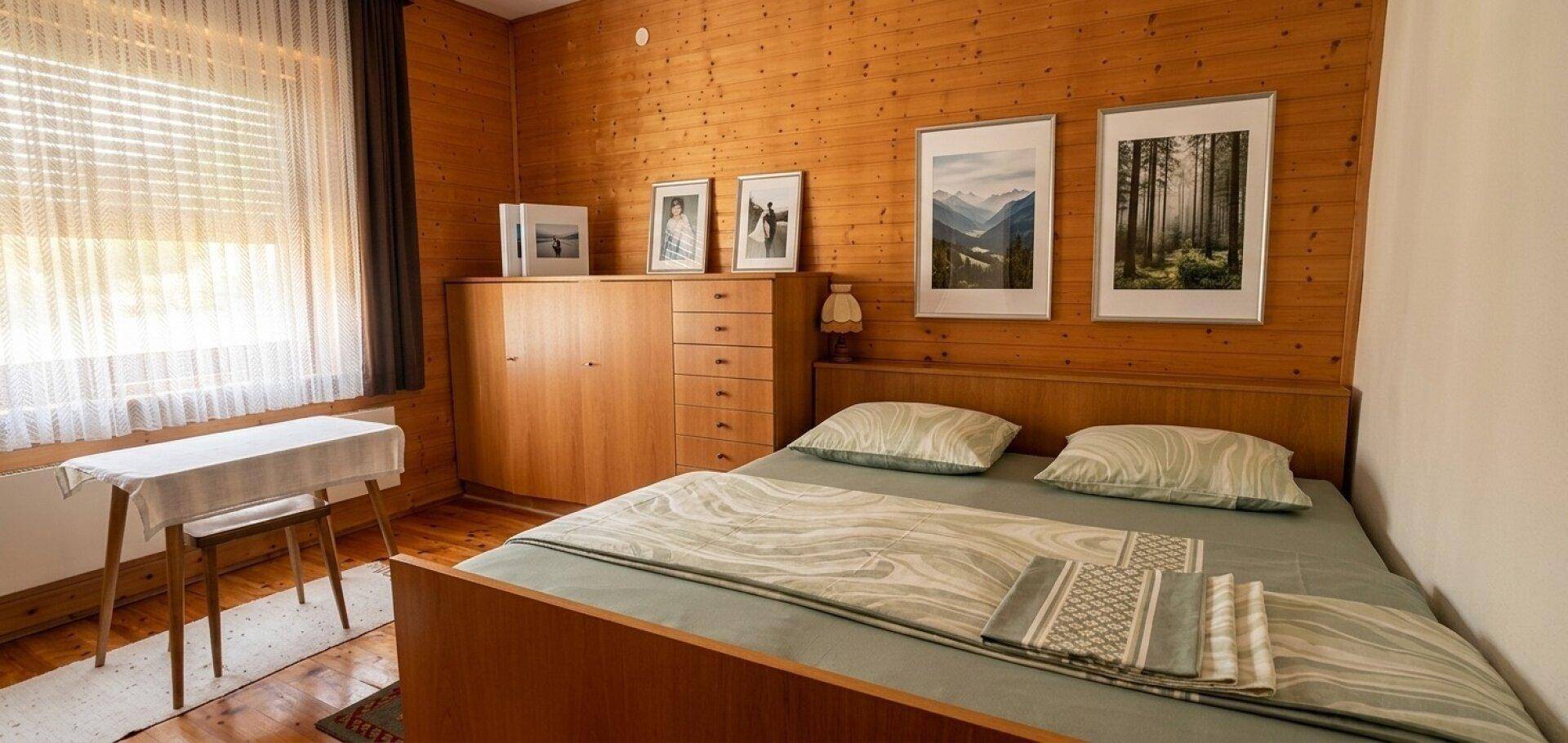 Gemütliches Schlafzimmer mit Holzwänden, einem Doppelbett und einem Holzschrank im traditionellen Stil.