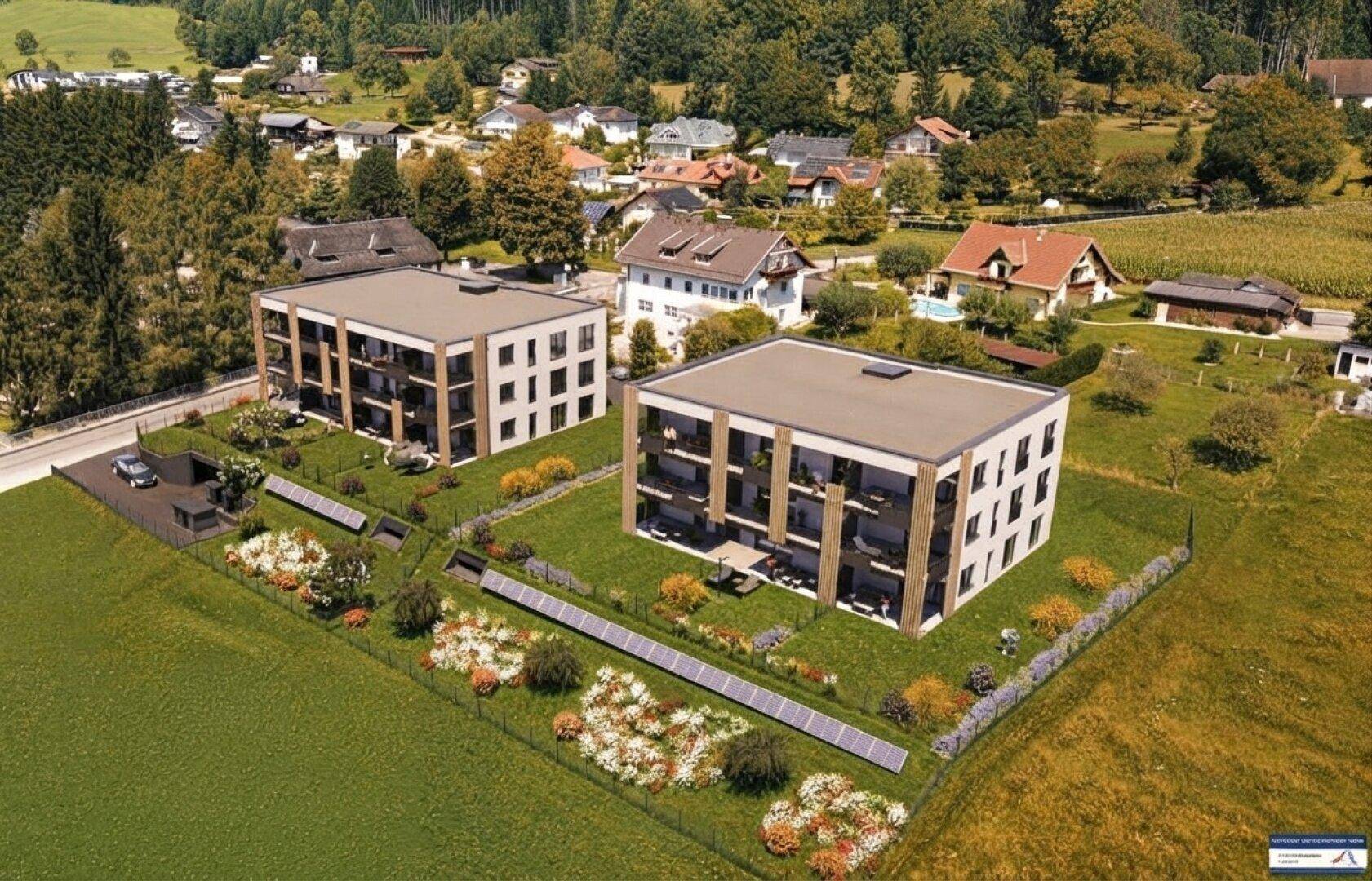 Luftaufnahme einer modernen Wohnanlage mit zwei Gebäuden, umgeben von Grünflächen und Solaranlagen.
