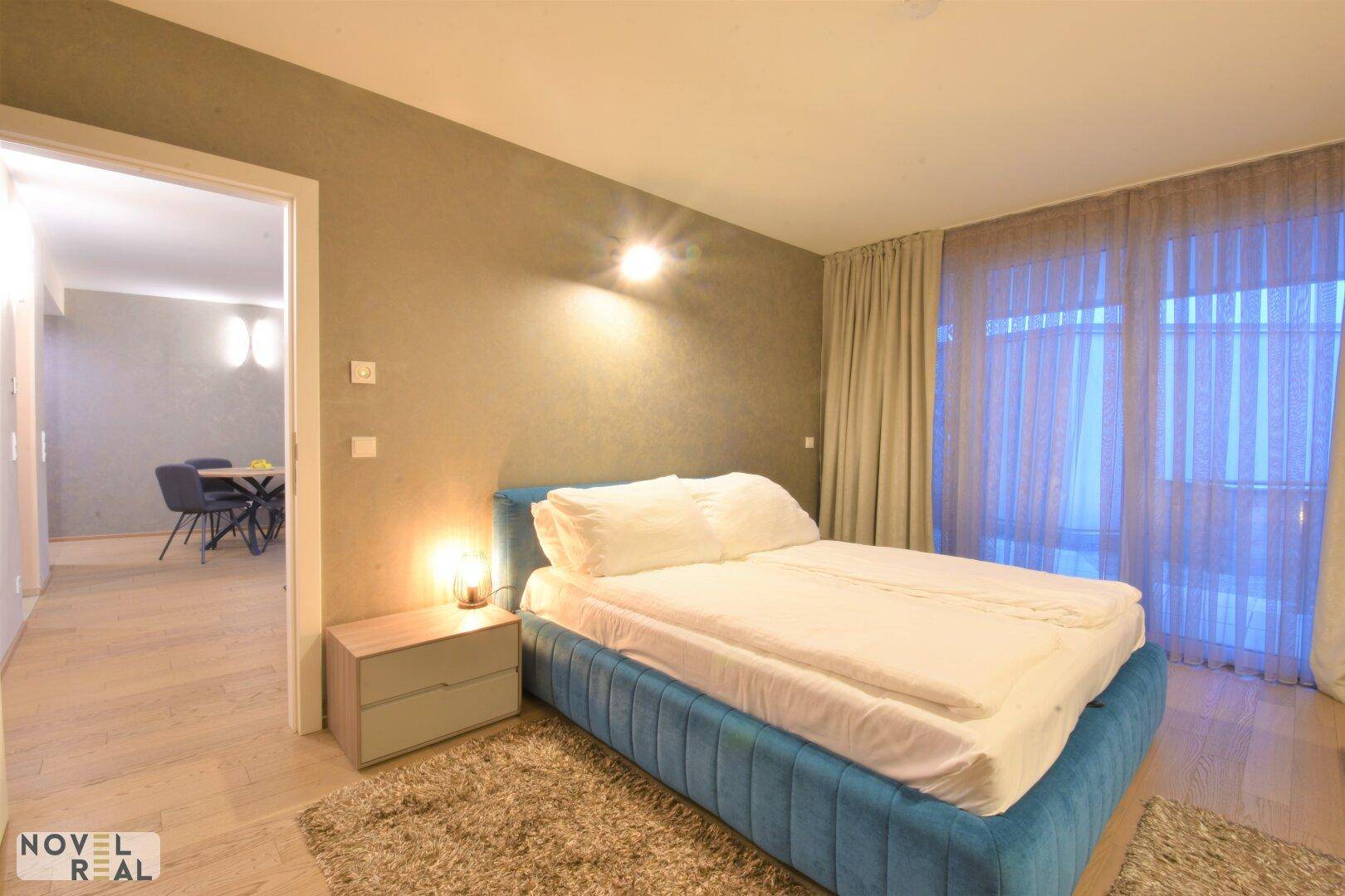 Schlafzimmer mit blauem Bettrahmen und Zugang zum offenen Wohnbereich.