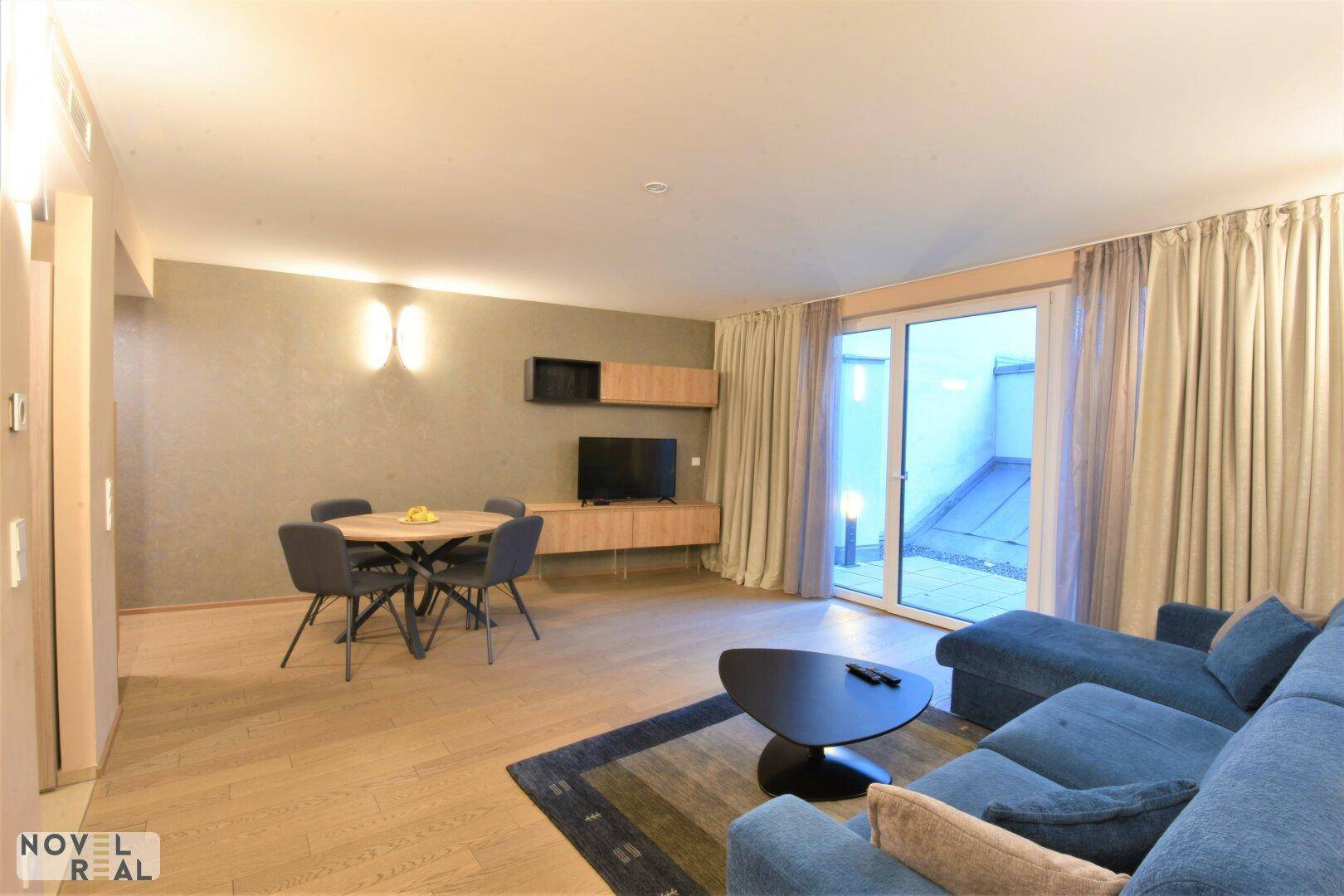 Gemütlicher Wohn- und Essbereich mit Sofa, Esstisch und Zugang zur Terrasse.