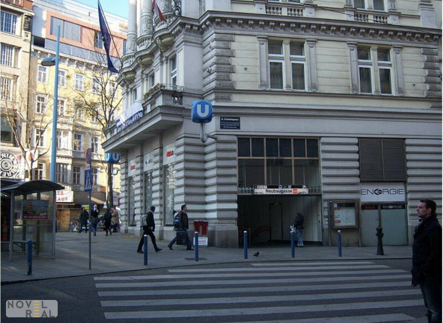 Historisches Gebäude an einer belebten Straße mit U-Bahn-Eingang in urbaner Umgebung.