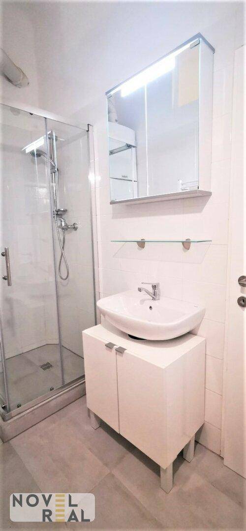 Modernes Badezimmer mit Duschkabine, Waschbecken und Spiegelschrank.