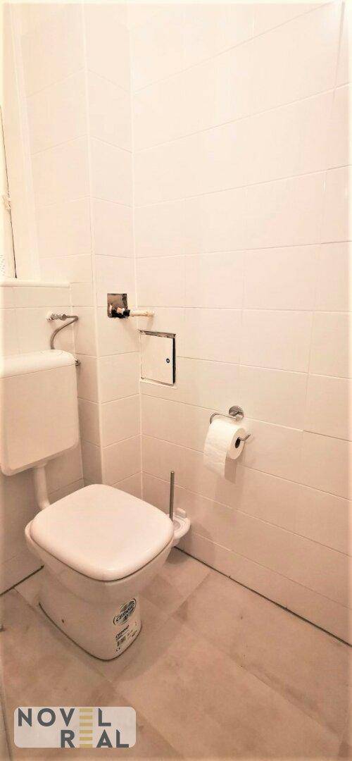 Helles WC mit weiß gefliesten Wänden und einfacher Ausstattung, ideal für Gäste.