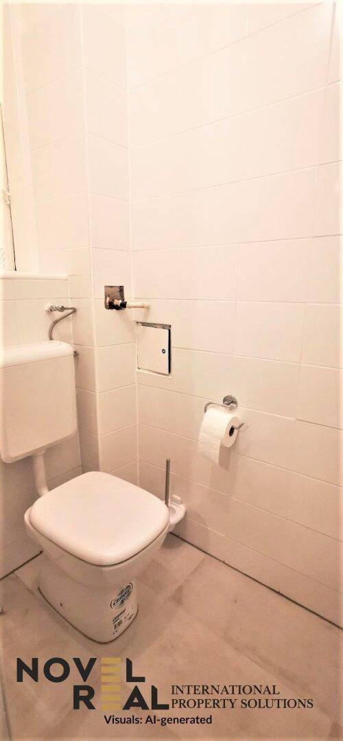 Kleines separates WC mit weißer Toilette und hellen Wandfliesen.