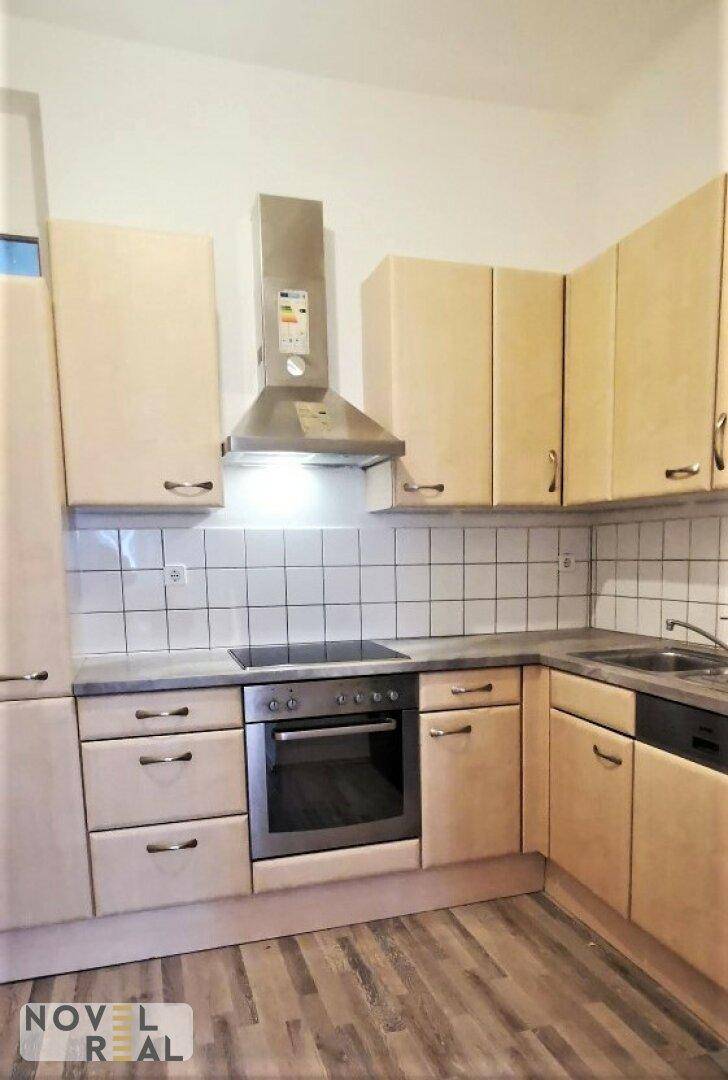 Funktionale Küche mit hellen Holzschränken, Fliesenrückwand und integriertem Backofen.