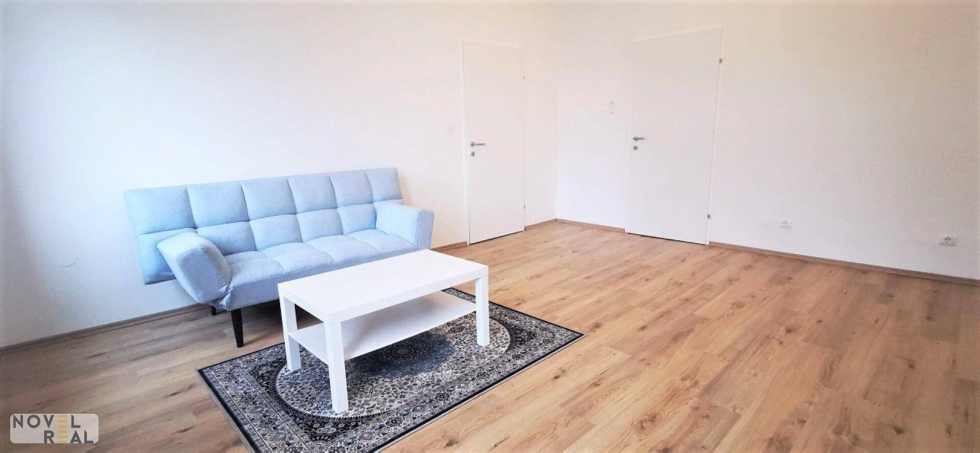 Helles Wohnzimmer mit Sofa, Couchtisch und zwei weißen Türen.