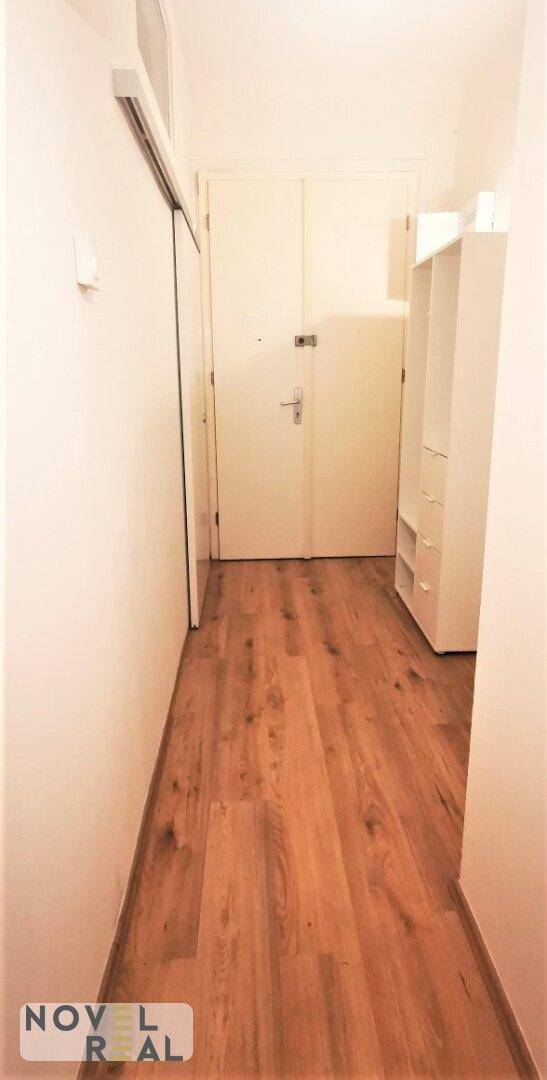 Heller Flur mit Laminatboden und weißer Tür.
