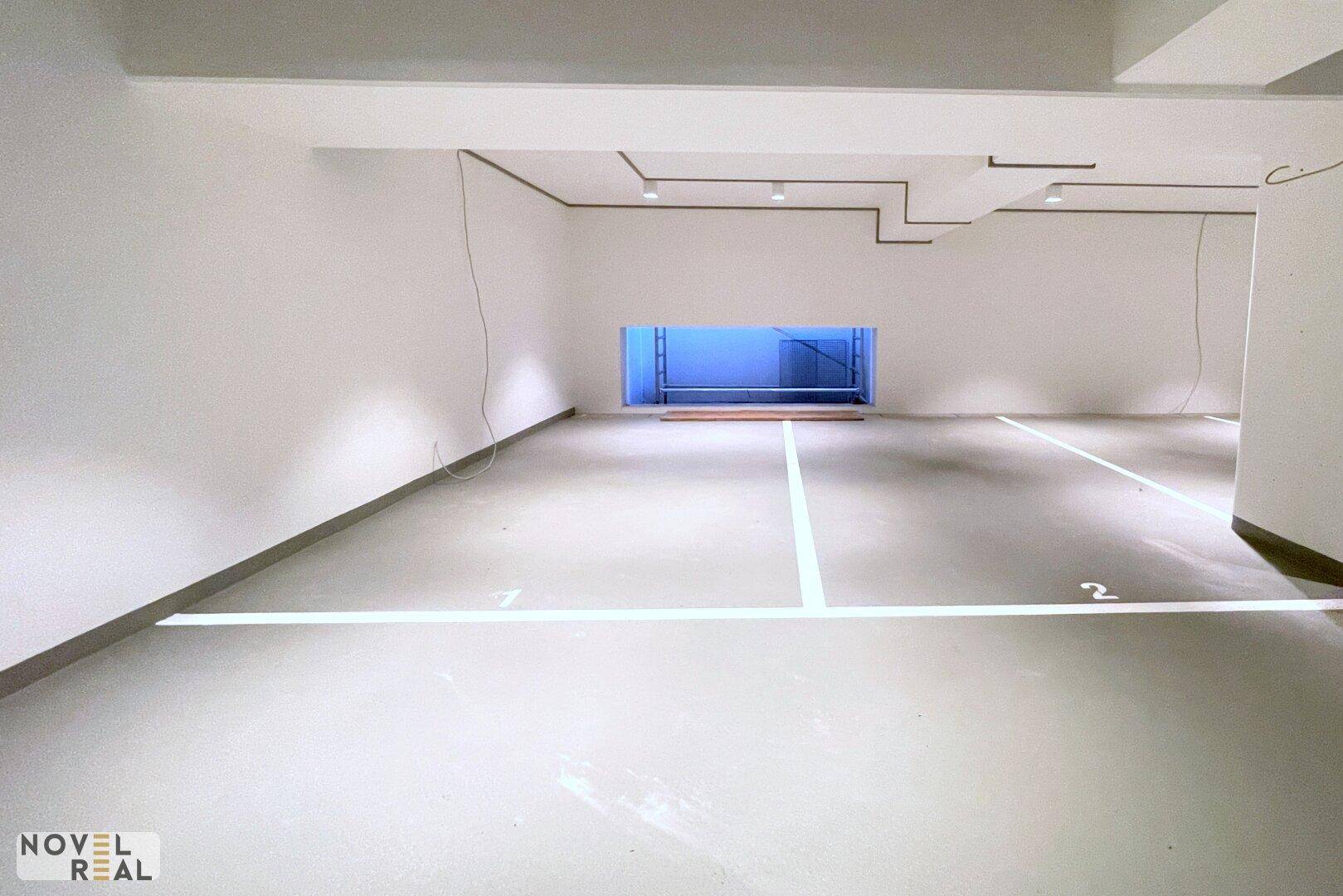 Geräumige Tiefgarage mit markierten Stellplätzen und heller Beleuchtung.