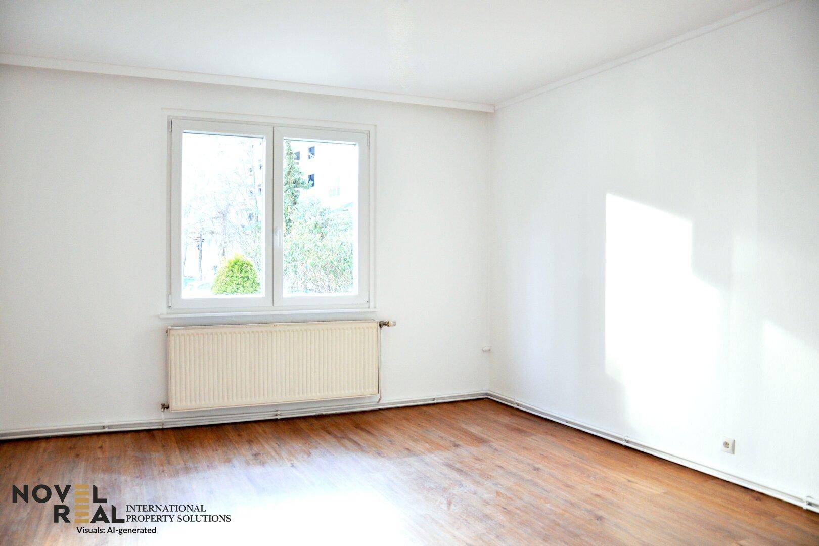 Leeres Schlafzimmer mit Holzboden, weiß gestrichenen Wänden und einem Fenster mit Heizkörper darunter.