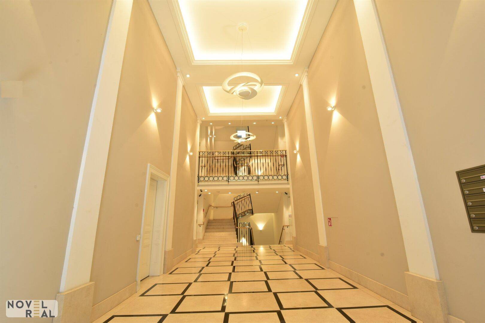 Großzügiger Eingangsbereich mit hohen Decken, gemustertem Fliesenboden und eleganter Treppe.