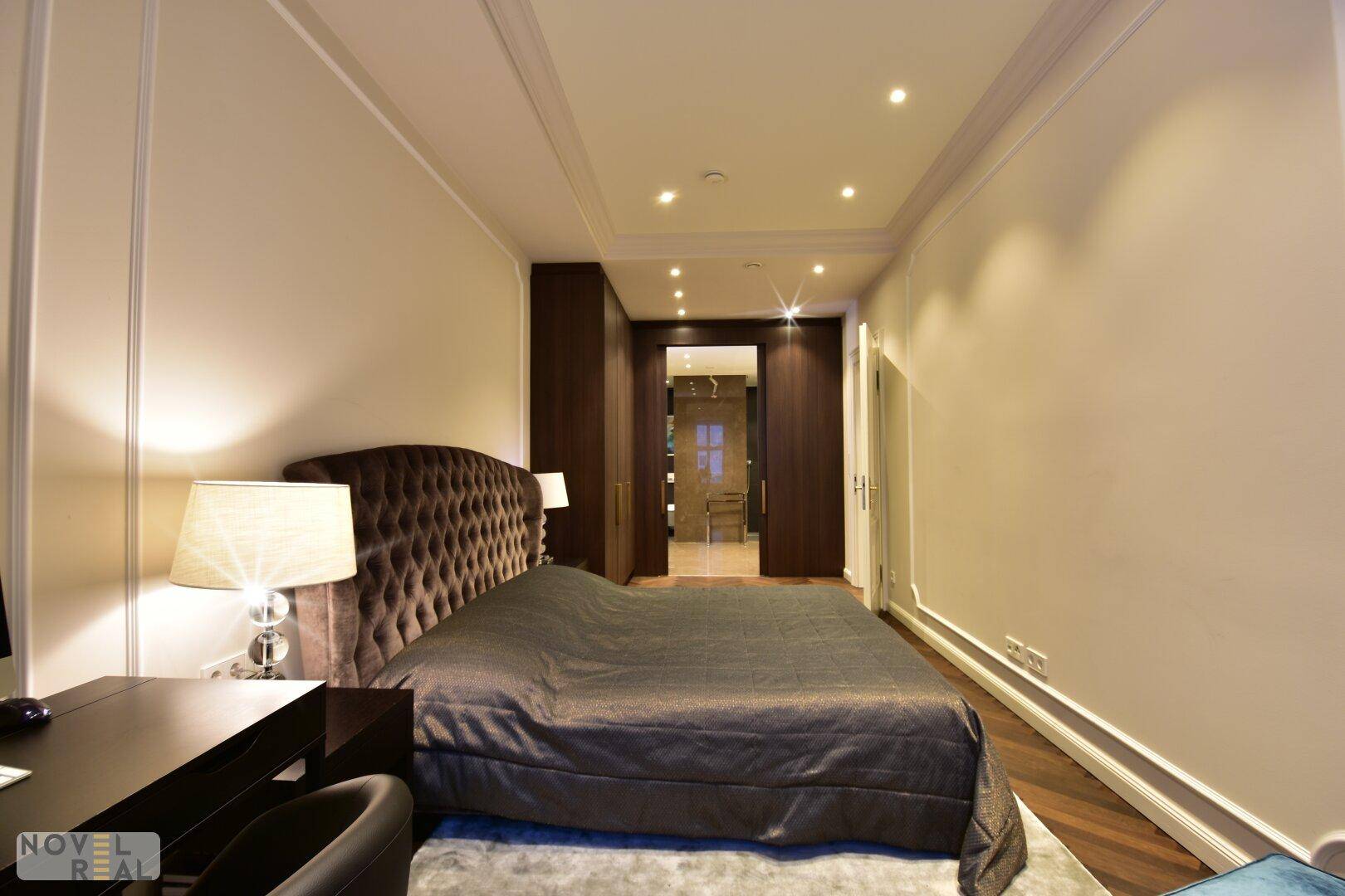 Komfortables Schlafzimmer mit Polsterbett und Blick auf das angrenzende Badezimmer.