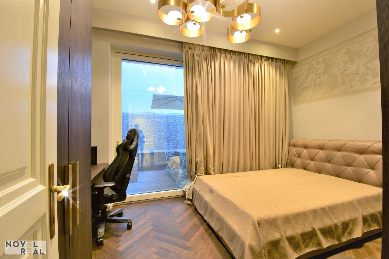 Helles Schlafzimmer mit Bett, Schreibtisch und Zugang zu einem Außenbereich.