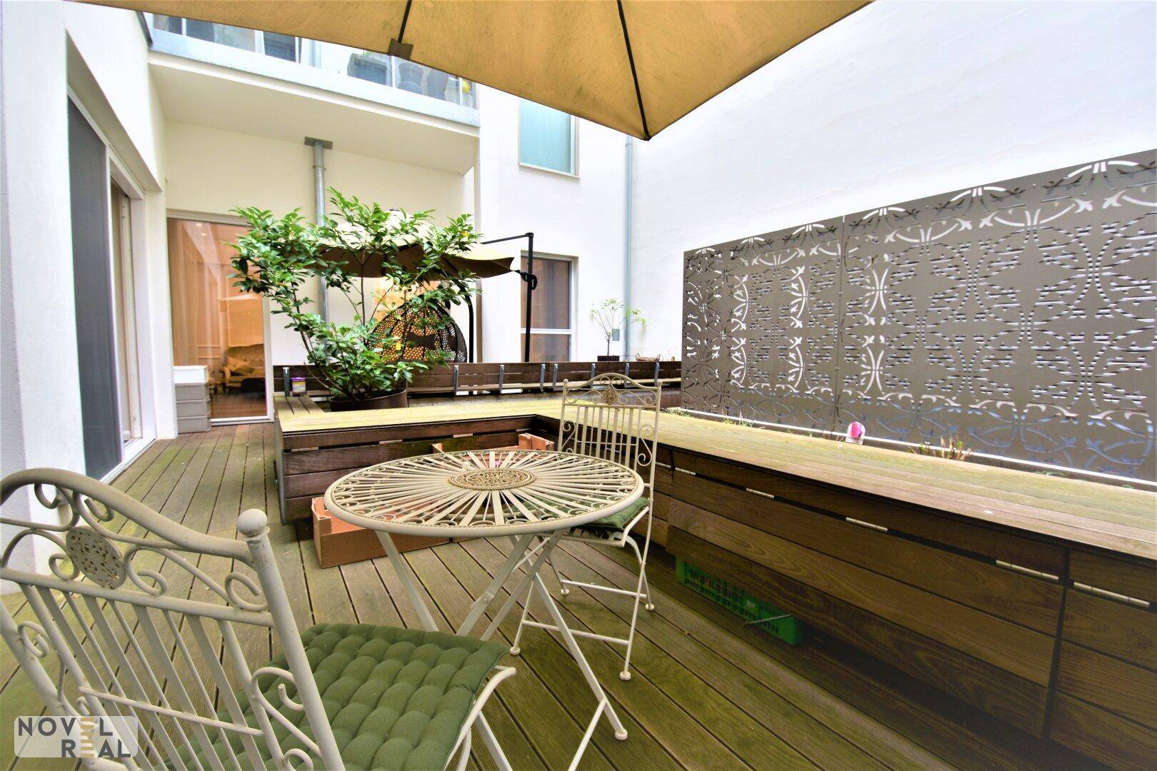 Gemütliche Terrasse mit schmiedeeisernen Gartenmöbeln und dekorativem Sichtschutz.