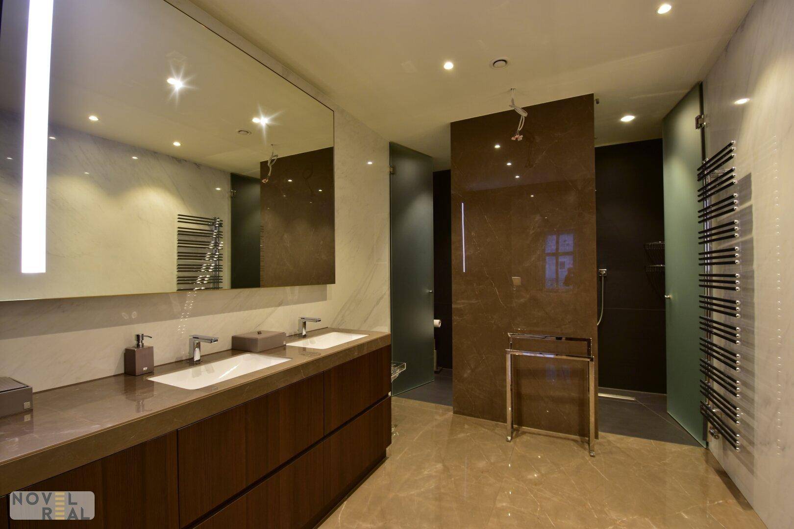 Modernes Badezimmer mit Doppelwaschbecken, großem Spiegel und begehbarer Dusche.