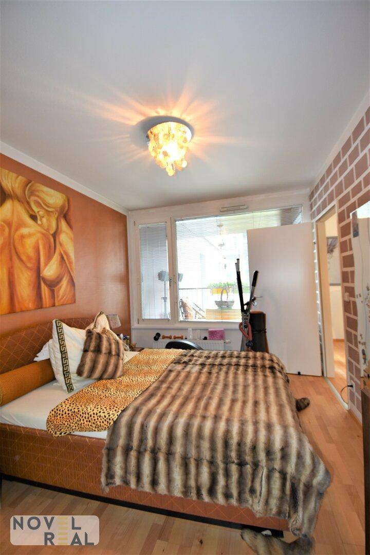 Schlafzimmer mit Doppelbett, Holzboden und Zugang zu einem weiteren Balkon.