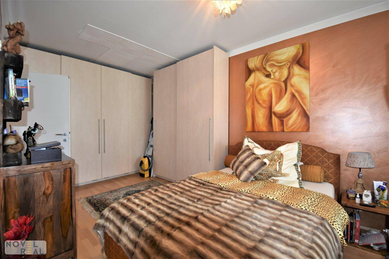 Geräumiges Schlafzimmer mit Einbauschränken, Holzboden und dekorativer Wandgestaltung.