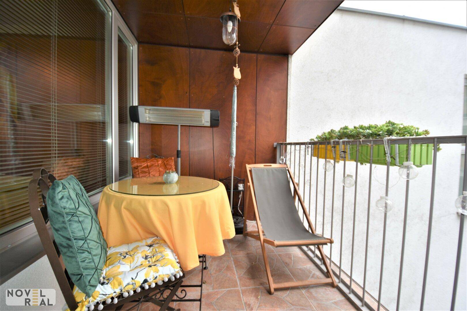 Möblierter Balkon mit Tisch, Stühlen und Heizstrahler für gemütliche Stunden im Freien.