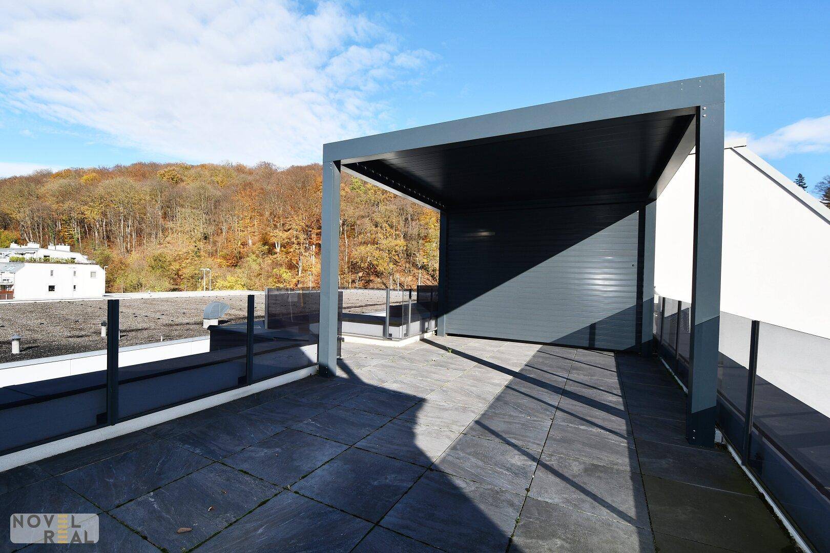 Weitläufige Dachterrasse mit Pergola und Panoramablick auf die umliegende Natur.