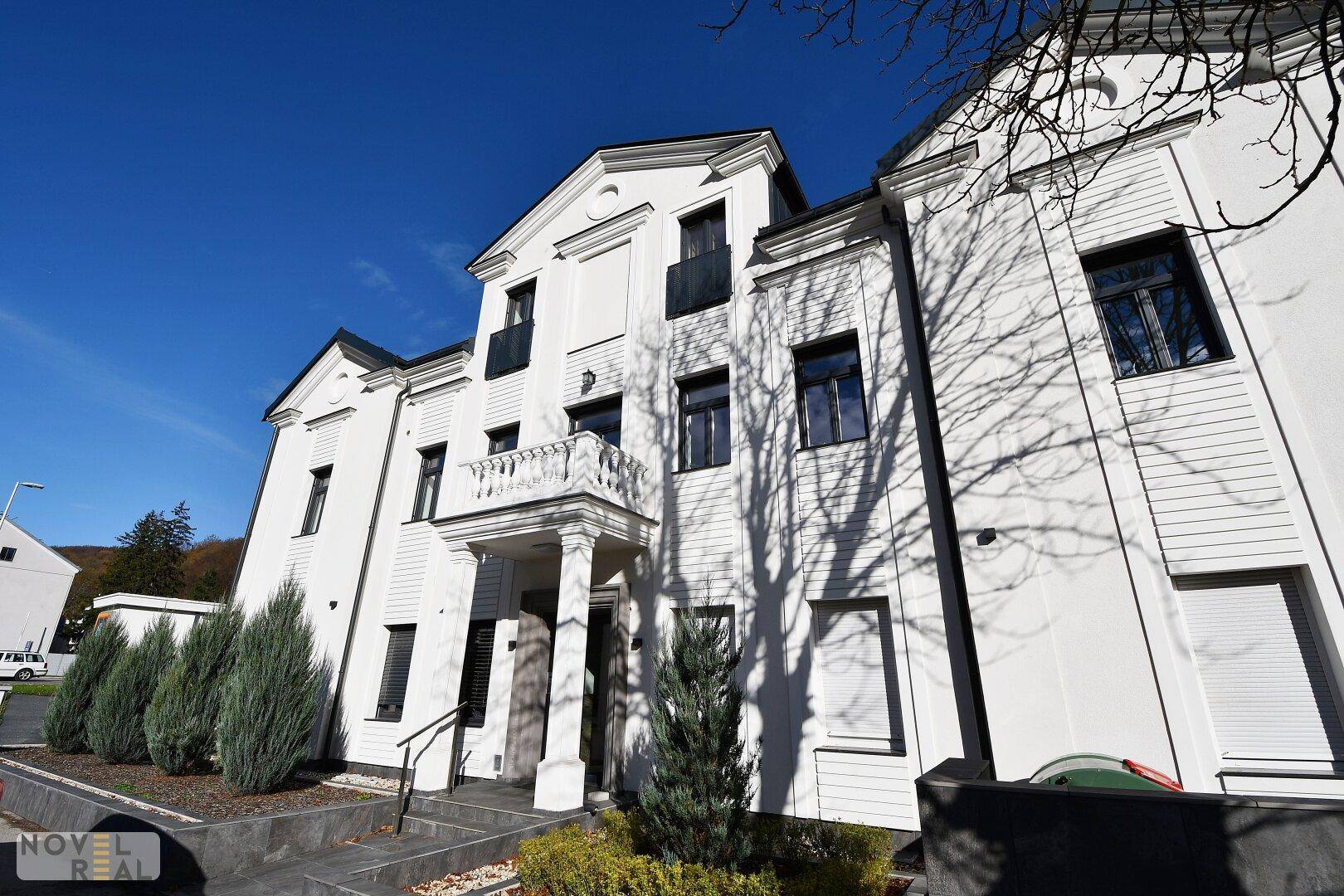 Elegantes Mehrfamilienhaus mit weißer Fassade und klassischer Architektur.