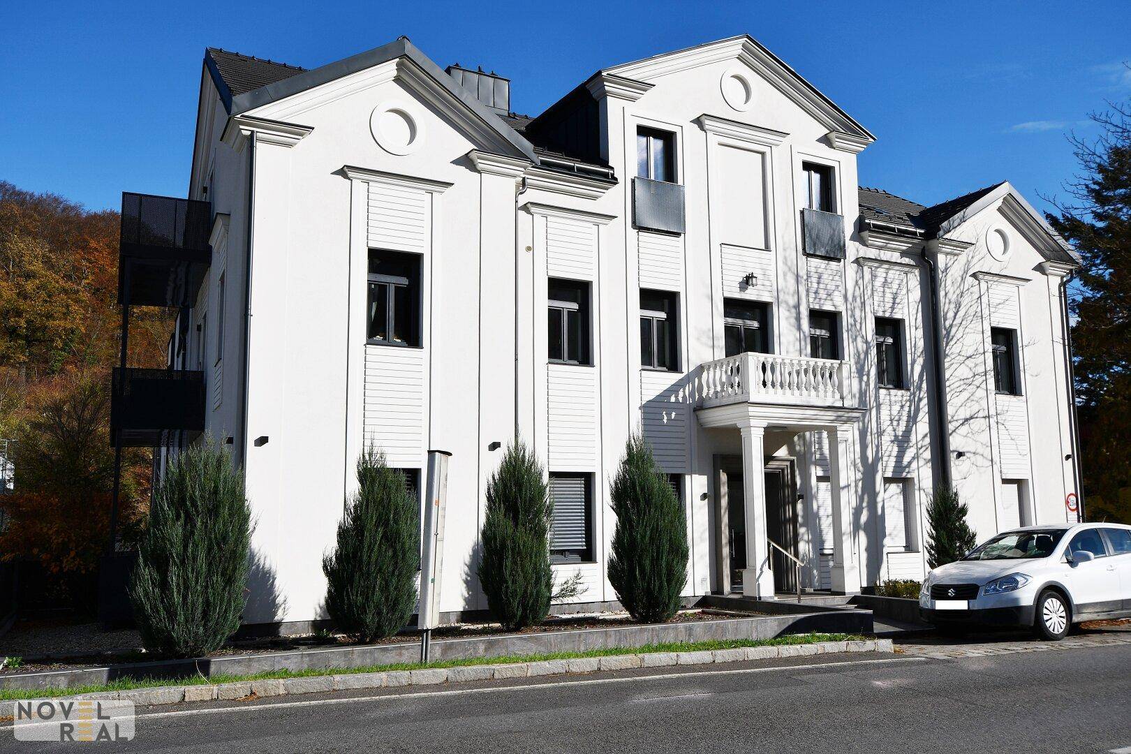 Attraktives Wohngebäude mit weißer Fassade, Balkonen und gepflegter Außenanlage.