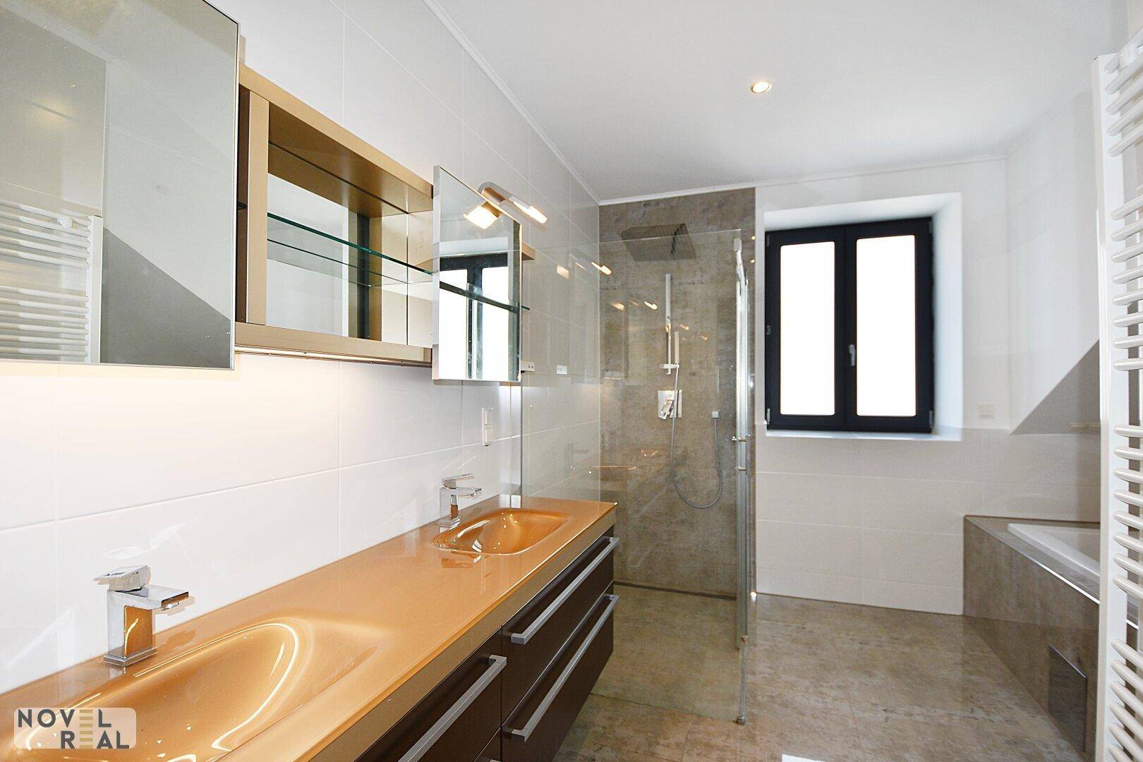 Modernes Badezimmer mit Doppelwaschbecken, begehbarer Dusche und Badewanne.