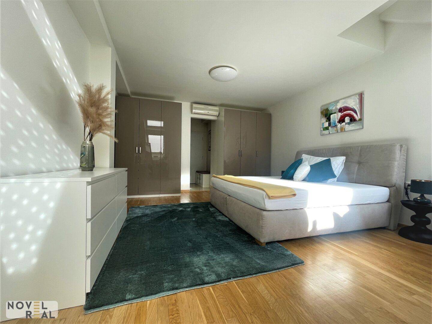 Geräumiges Schlafzimmer mit Holzboden, großem Bett und Einbauschränken, hell beleuchtet.