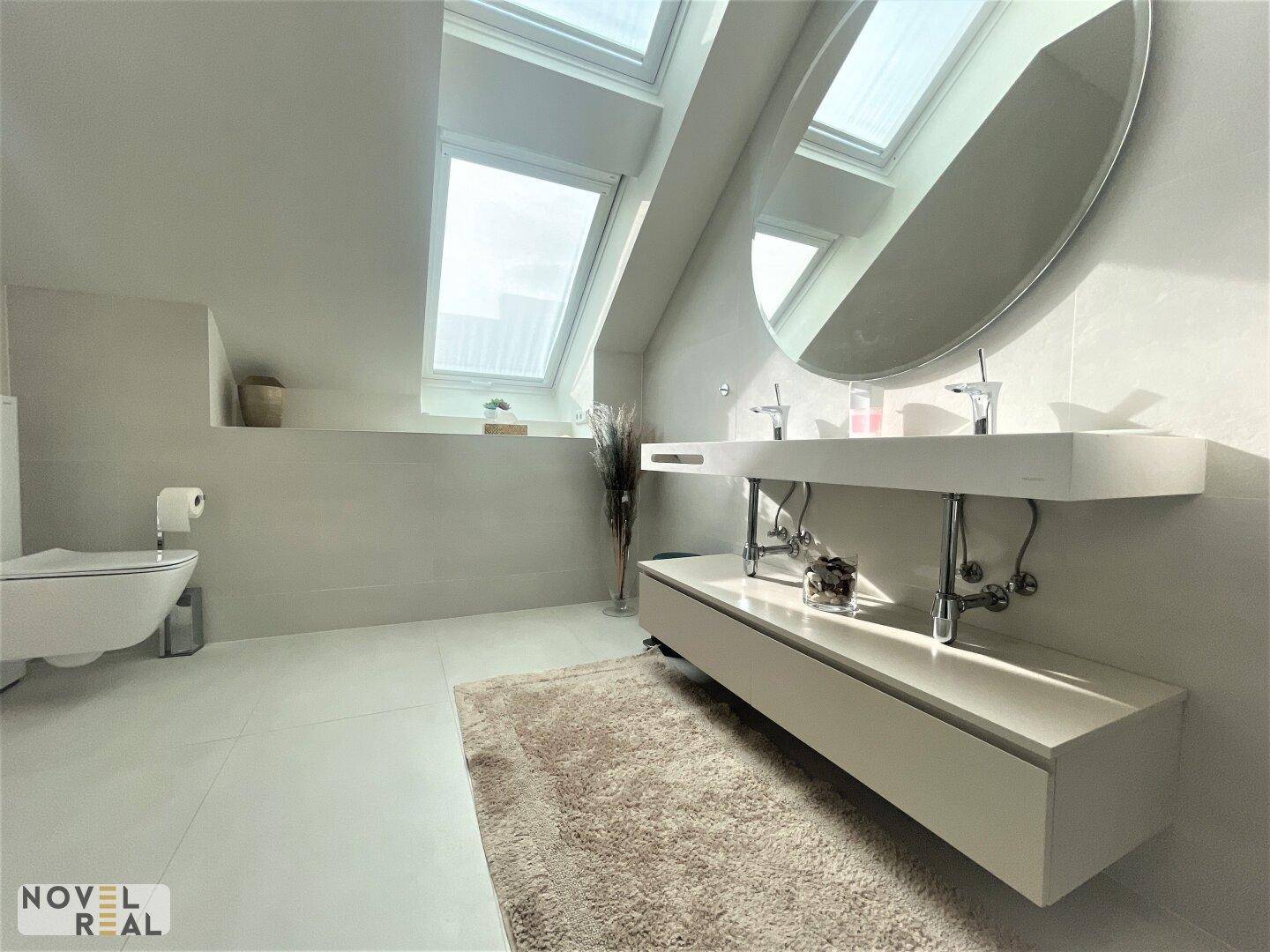 Modernes Badezimmer mit schwebendem Waschtisch, Wand-WC und viel Tageslicht durch Dachfenster.