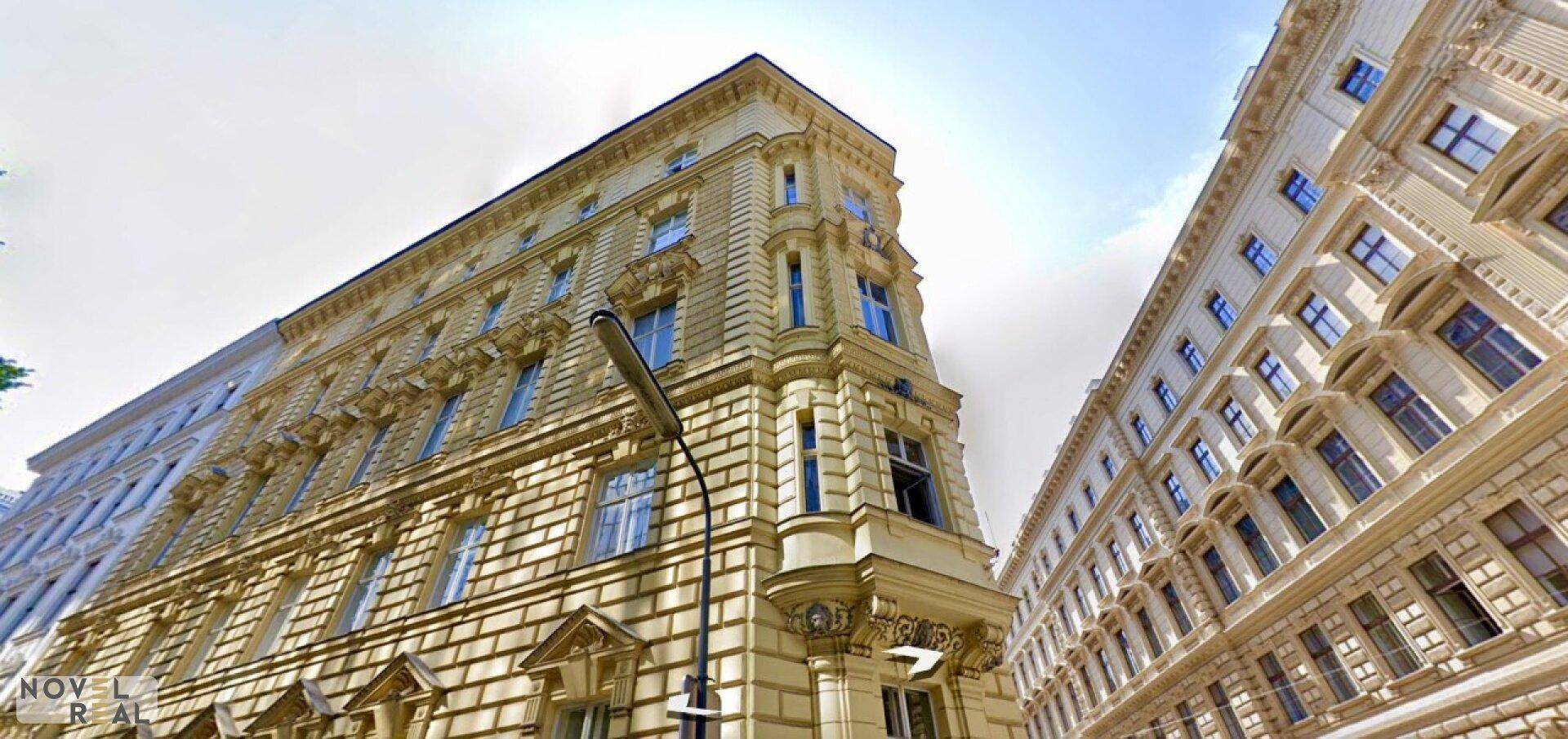 Historisches Eckgebäude mit aufwendiger Fassade und vielen Fenstern unter blauem Himmel.
